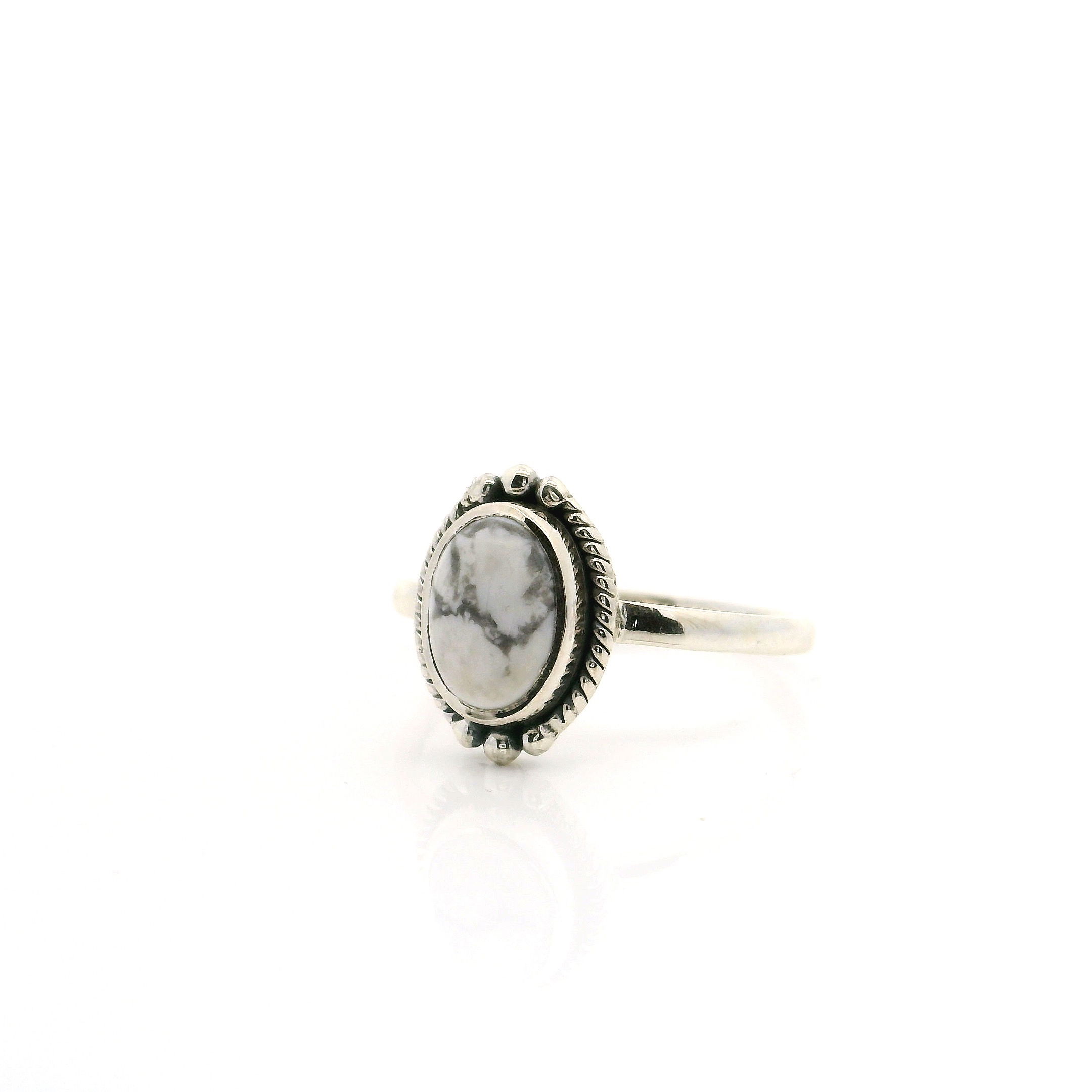 Showcase your unique style with this stunning Howlite Ring, crafted in a size 6 for a comfortable fit. The oval cabochon Howlite stone features gorgeous gray bucking horse veining, making each piece one of a kind. Encased in a finely detailed 925 sterling silver bezel with intricate rope and beaded accents, this ring blends classic elegance with a touch of Southwestern flair. Perfect for everyday wear or as a standout piece for special occasions, it’s a must-have addition to any women's jewelry collection. Howlite Ring - Oval Cabochon with Gray Bucking Horse Veining & Rope & Beaded Detail Bezel Set in 925 Sterling Silver sz6