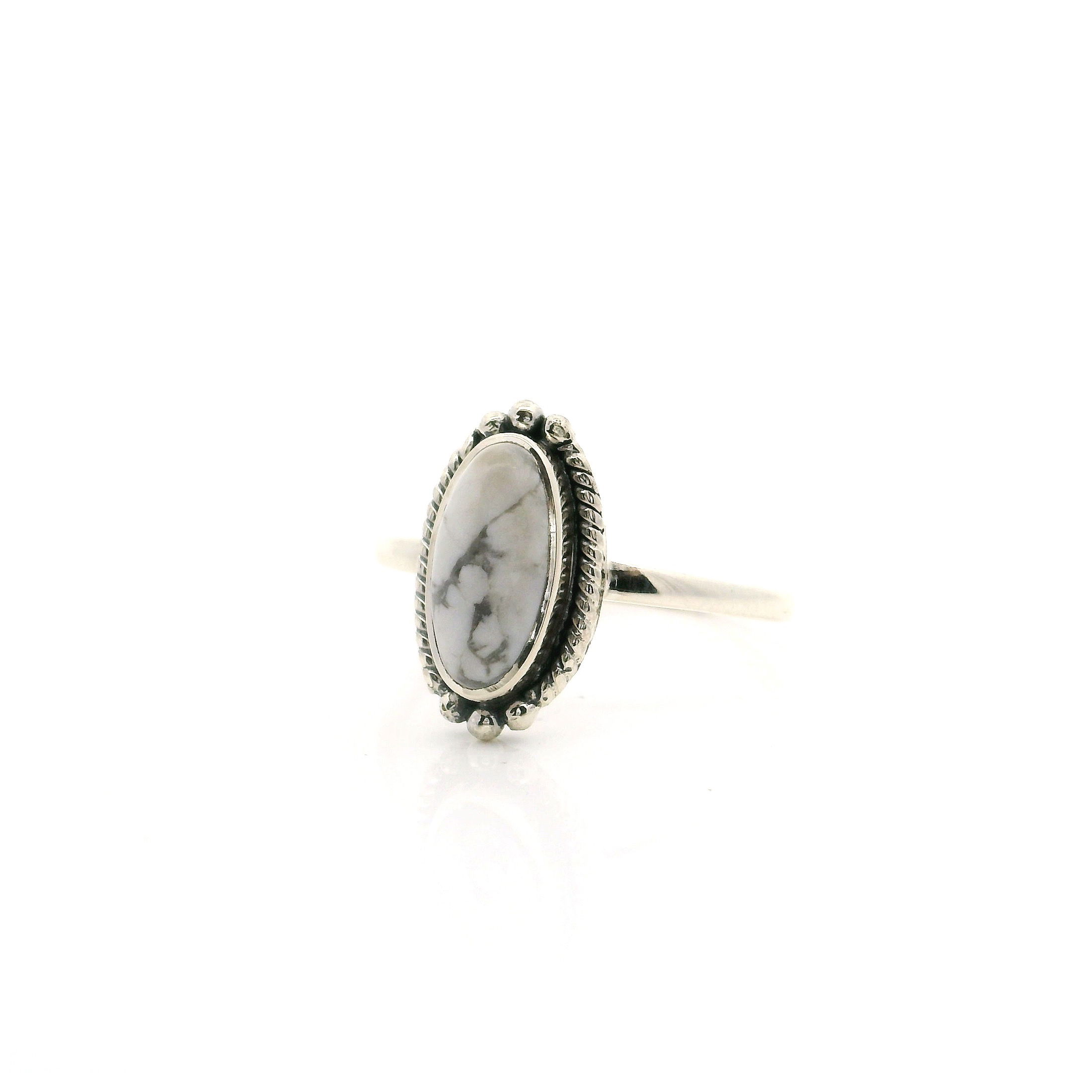 Elevate your everyday elegance with this striking Howlite Ring, featuring a smooth oval cabochon adorned with delicate gray veining. The gemstone is bezel set in gleaming 925 sterling silver, highlighted by intricately braided rope and beaded detailing around the band for a touch of vintage-inspired charm. Perfectly sized for a finger size 7, this ring combines natural beauty and artisan craftsmanship, making it a versatile statement piece for any jewelry collection. Ideal for gifting or personal indulgence, this howlite ring adds a calming touch and sophisticated sparkle to every outfit. Howlite Ring - Oval Cabochon with Thin Gray Veining with Rope & Beaded Detail Bezel Set in 925 Sterling Silver sz7