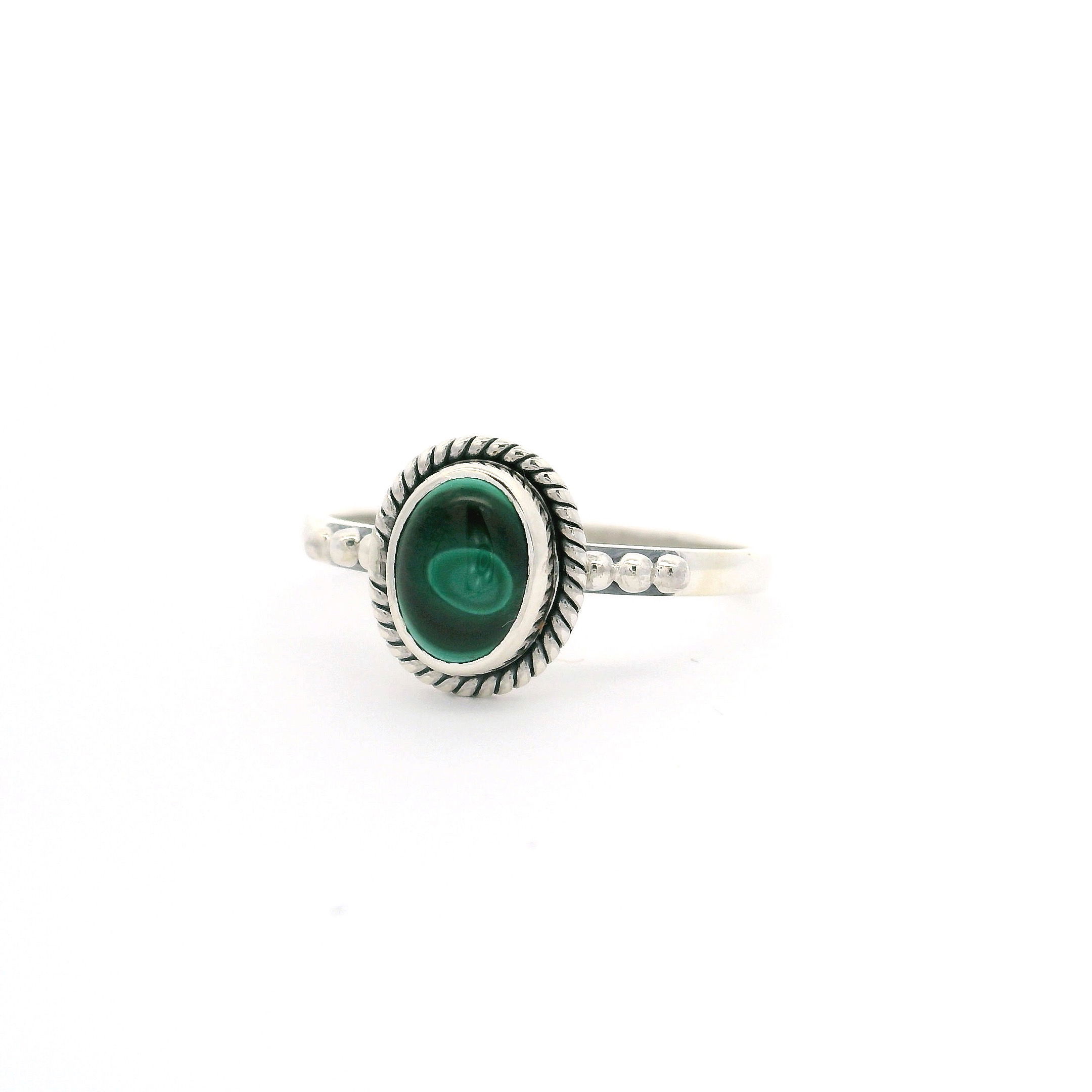 Discover the captivating beauty of our Malachite Ring, crafted for those who appreciate unique elegance. This dainty piece features a dark green oval malachite cabochon, highlighted by a mesmerizing single light green “eye.” Expertly bezel set in gleaming 925 sterling silver, the ring is adorned with intricate rope detailing that accentuates the stone’s natural allure. The triple beaded band elevates this ring with subtle sophistication and texture. Perfect as a statement piece or an everyday favorite, this size 10 ring is a must-have addition to any jewelry collection. Malachite Ring - Dainty Dark Green Oval Cabochon with Single Light Green Eye Bezel Set with Rope Detail on Triple Beaded Band in 925 Sterling Silver sz10