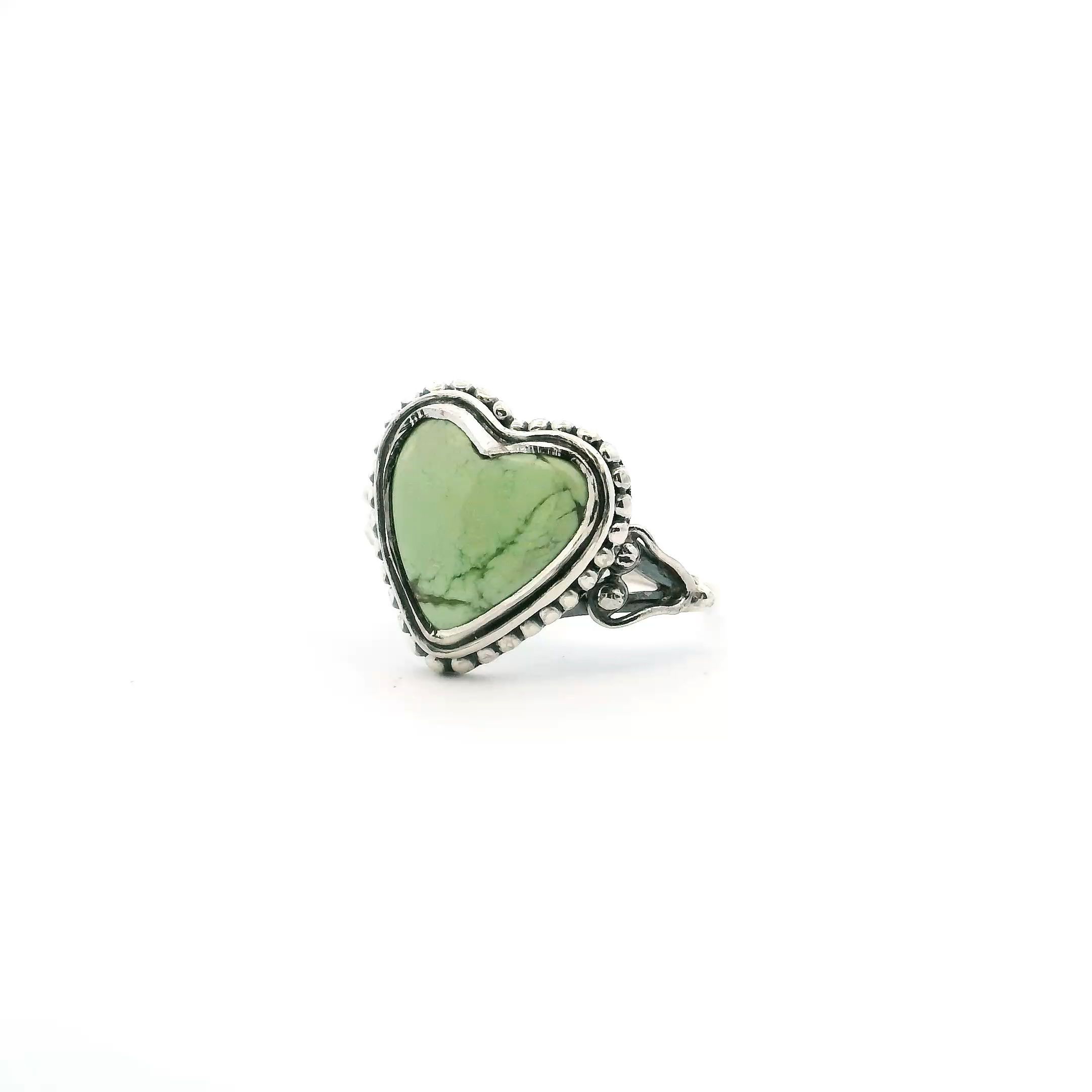 Elevate your jewelry collection with this exquisite Lemon Chrysoprase Ring, beautifully crafted in 925 sterling silver. The centerpiece showcases a heart-shaped lemon chrysoprase cabochon, adorned with enchanting darker green inclusions that make each ring uniquely captivating. Expertly bezel-set, the stone is framed by elegant beaded accents, delicately enhancing its natural beauty. The double band adds a contemporary flair while ensuring a comfortable, secure fit in size 7. Perfect as a statement piece or a thoughtful gift, this ring celebrates the harmonious blend of classic artistry and modern design. Lemon Chrysoprase Ring - Heart Cabochon with Darker Green Inclusions Bezel Set with Beaded Accents on Double Band in 925 Sterling Silver sz7