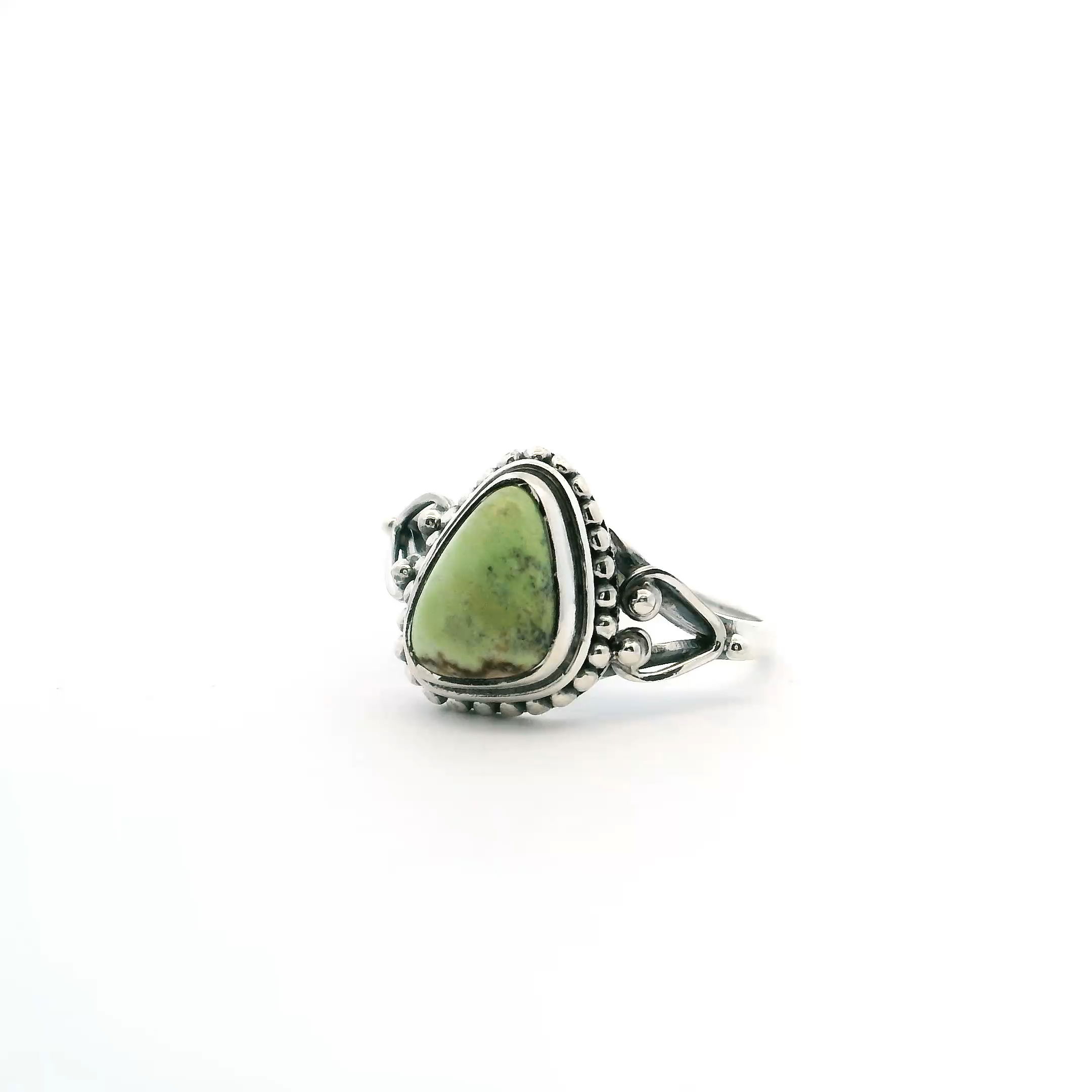 Elevate your style with this striking Lemon Chrysoprase Ring, expertly crafted in 925 sterling silver. Showcasing a unique triangular freeform cabochon, the vibrant lemon-green gemstone features a distinctive dark brown inclusion along the bottom edge, adding natural intrigue and character. The bezel setting is accented with delicate beaded detailing, enhancing its artisanal charm. Lemon Chrysoprase Ring - Triangular Freeform Cabochon with Dark Brown Inclusion Along Bottom Edge Bezel Set with Beaded Detail in 925 Sterling Silver sz8