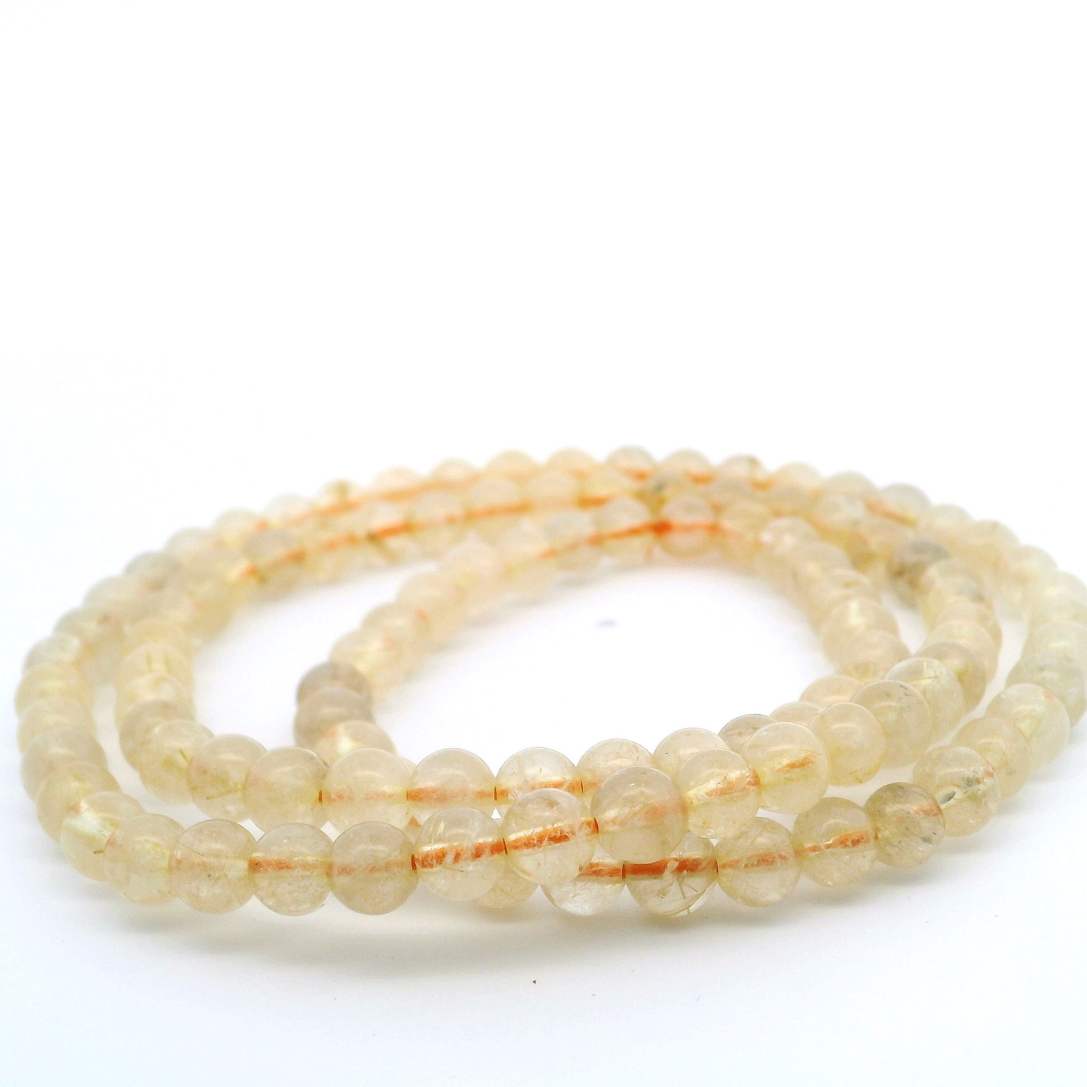 Elevate your style with the luminous allure of this Golden Rutile Quartz Beaded Necklace. Each 6mm round bead reveals intricate golden threads suspended within clear quartz, capturing light with captivating brilliance. Expertly strung for seamless elegance, this necklace blends subtle sophistication with striking charm, perfect for daily wear or special occasions. Embrace the natural warmth and positive energy of golden rutile quartz, making this piece a distinctive addition to your collection or a meaningful gift. Golden Rutile Quartz Beaded Necklace - 6mm Rounds