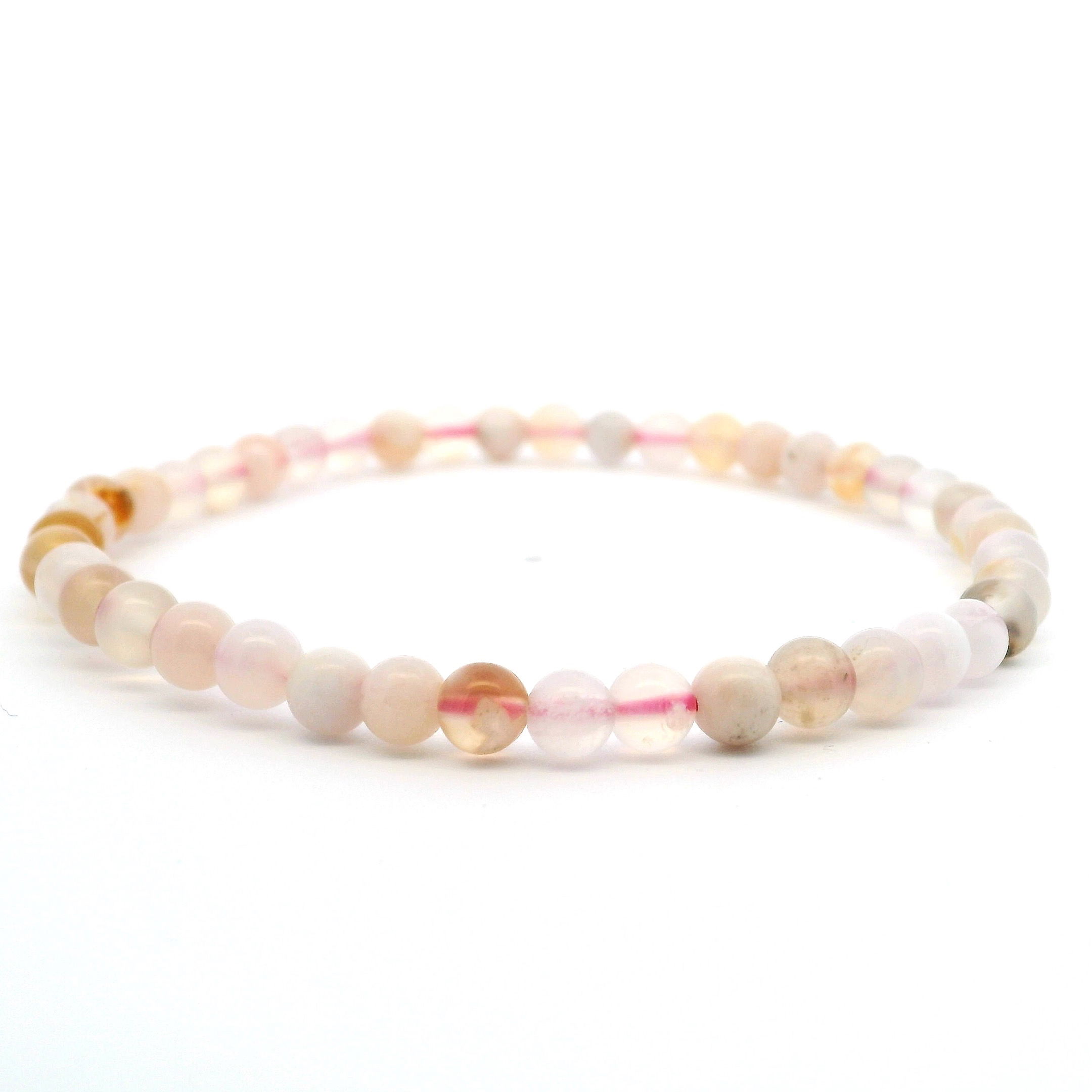 Elevate your everyday style with our Flower Agate Beaded Bracelet, showcasing delicate 4mm round beads in soft, natural pastel tones. Each genuine Flower Agate bead reveals unique, floral-like inclusions that symbolize growth, harmony, and emotional healing. Strung on a durable stretch cord for effortless comfort, this lightweight bracelet is perfect for layering or wearing solo. A subtle yet meaningful accessory, it brings gentle beauty and mindful energy to any jewelry collection. Flower Agate Beaded Bracelet - 4mm Rounds