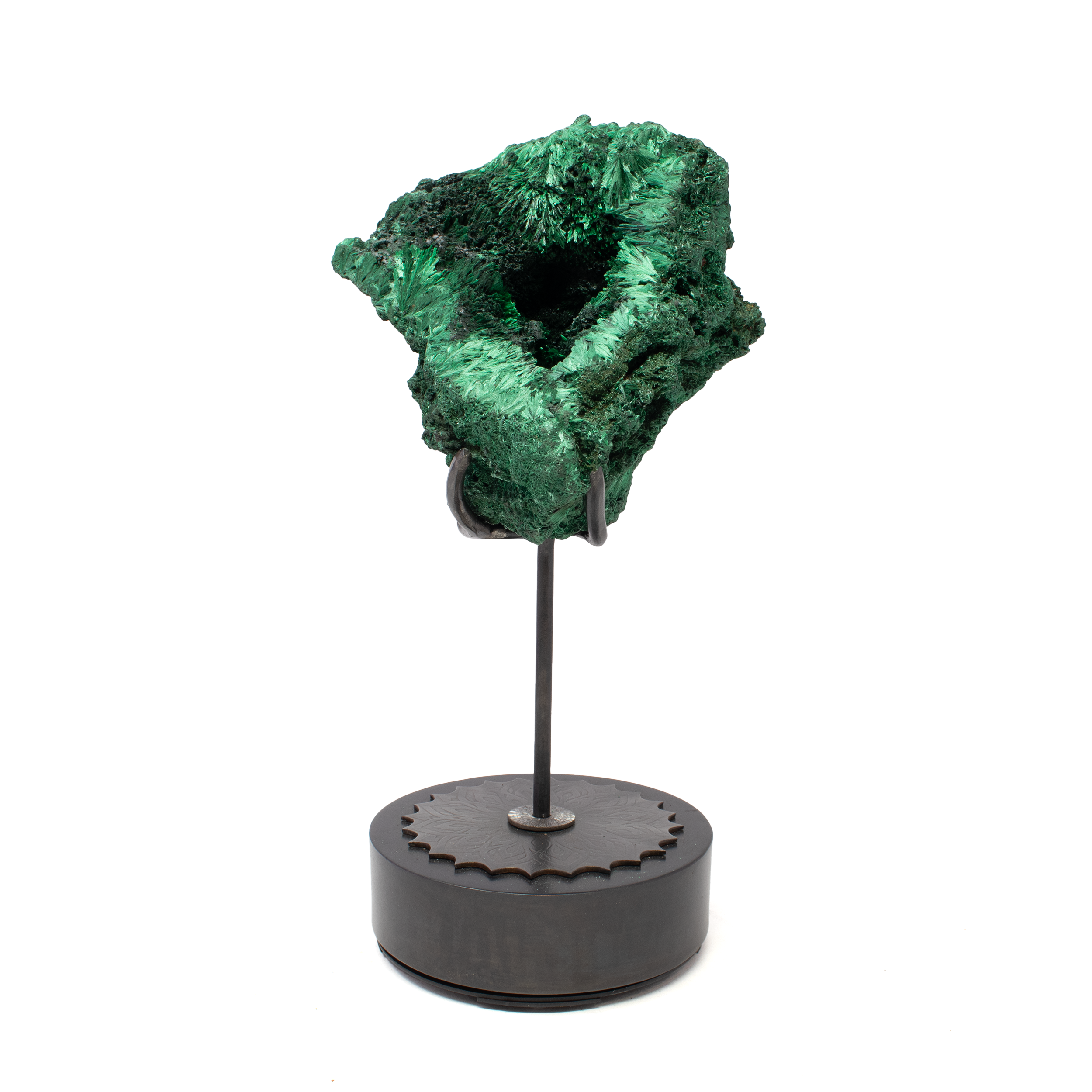 Elevate your space with the Chatoyant Malachite Specimen, showcased on a custom-etched spinning stand that brings movement and brilliance to this extraordinary piece. Vivid, fibrous bands of deep green malachite ripple across the surface, revealing its signature chatoyance and storied copper-rich origins. A naturally formed vug adds depth and raw elegance, inviting a closer look into the mineral’s organic architecture. Resting on a sleek round base, the rotating design offers a full 360-degree view, allowing every facet to gleam in shifting light. A bold fusion of natural artistry and refined presentation, this specimen is a standout centerpiece for collectors, interior connoisseurs, and admirers of the earth’s most mesmerizing creations. Chatoyant Malachite Specimen on Custom Etched Spinning Stand - Fiberous with Vug on Round Base