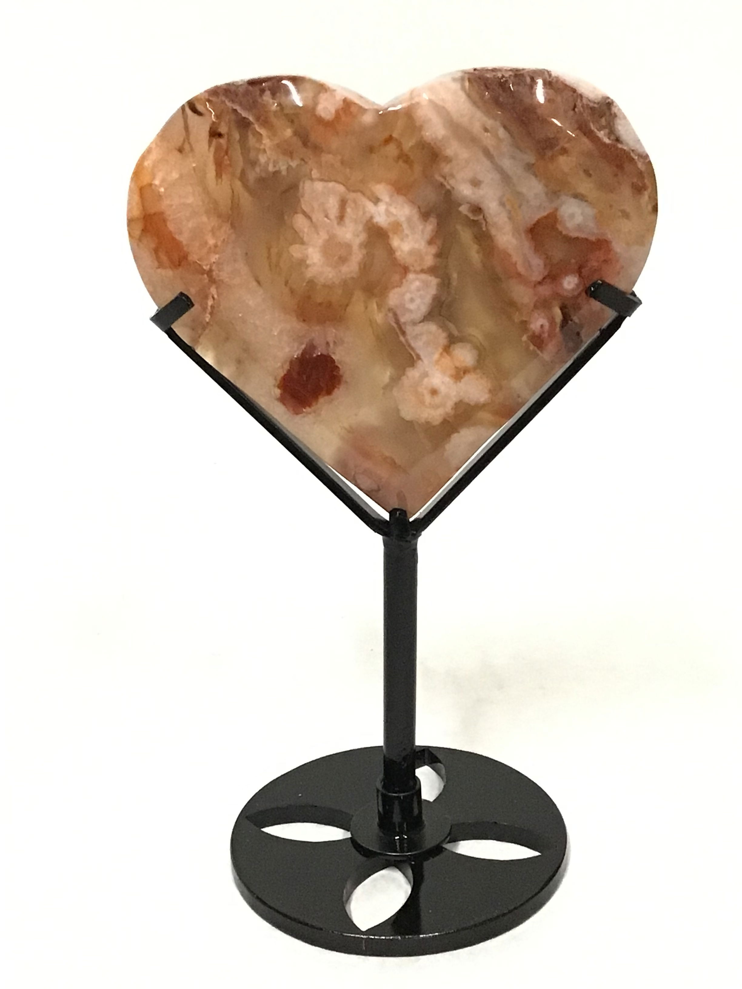 Elevate your crystal collection with this exquisite Flower Carnelian Heart, expertly displayed on a custom-fitted metal stand. This exceptional piece features delicate peach-hued flower formations highlighted by a breathtaking red inclusion, swirling through the carnelian with vibrant energy. The heart is further enhanced by two sparkling druzy vugs—natural pockets glistening with tiny crystal points—creating points of mesmerizing interest. Gracefully sculpted with smooth geometric lines, this carnelian heart not only embodies romance and emotional balance but also serves as a radiant centerpiece for any space. unforgettable addition to any crystal lover's trove. Flower Carnelian Heart on Fitted Metal Stand - Peach Flowers with Stunning Red Inclusion & Two Druzy Vugs