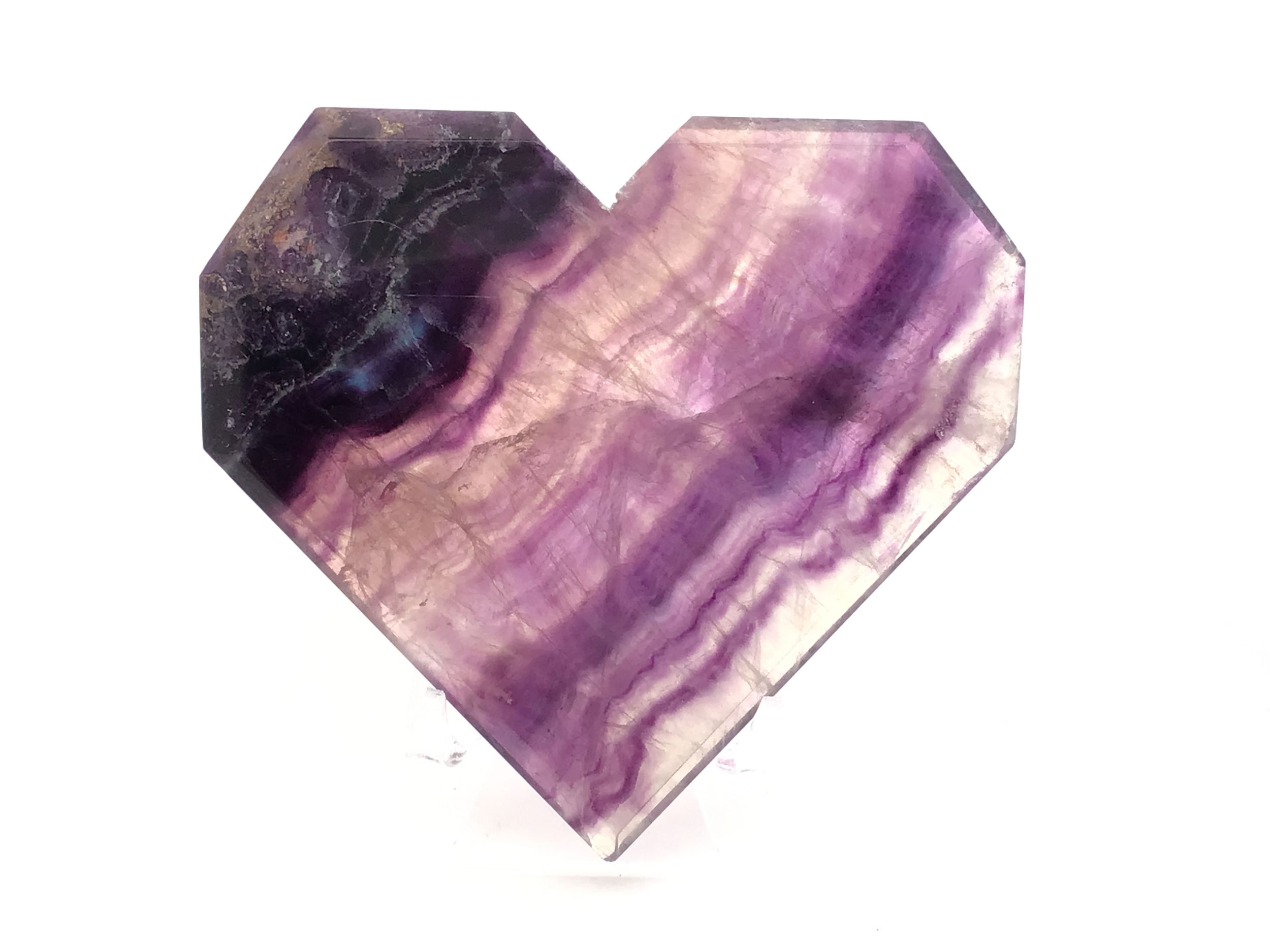Illuminate your space with the mesmerizing beauty of our Rainbow Fluorite Heart – Flat with Faceted Faces on a sleek Lucite Stand. This exquisite crystal heart showcases striking diagonal purple banding, highlighting nature’s artistry within every unique piece. Carefully shaped with geometric precision and finished with multiple faceted surfaces, it catches and reflects light from every angle. Resting elegantly on its crystal-clear Lucite base, this heart is both a stunning decor accent and a meaningful symbol of harmony and transformation. Rainbow Fluorite Heart - Flat with Faceted Faces on Lucite Stand (Diagonal Purple Banding)