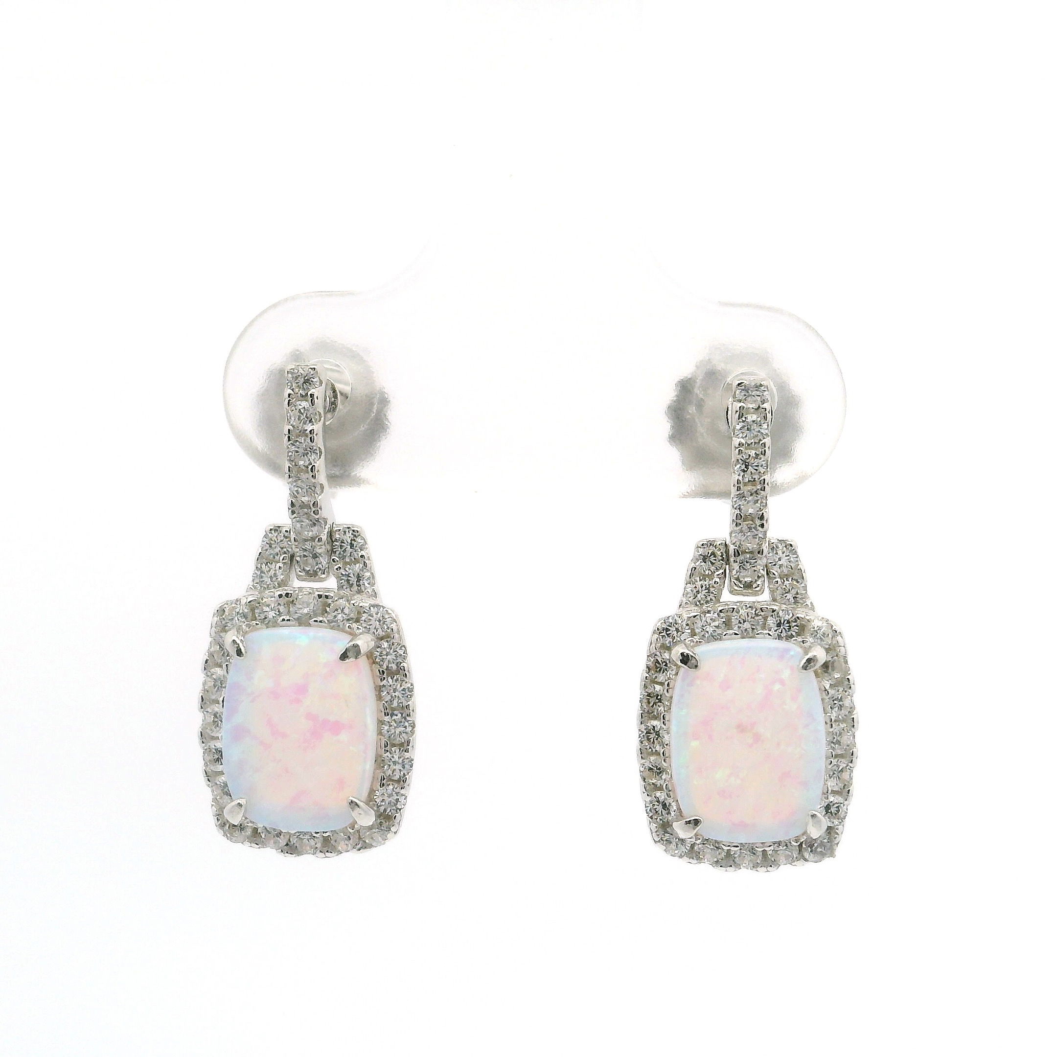 Elevate your elegance with these White Opal Rectangle Cabochon Earrings, exquisitely set in 925 Sterling Silver. Each stud showcases a luminous white opal, artfully framed by dazzling white CZs in a surrounding prong setting and accentuated by a graceful CZ-encrusted bail. The sleek, rectangular cabochon cut highlights the opal’s natural iridescence, while premium Swarovski crystals add extra brilliance. White Opal Earrings on Post - Rectangle Cabochon with White CZs in Bail & Surrounding Prong Setting in 925 Sterling Silver