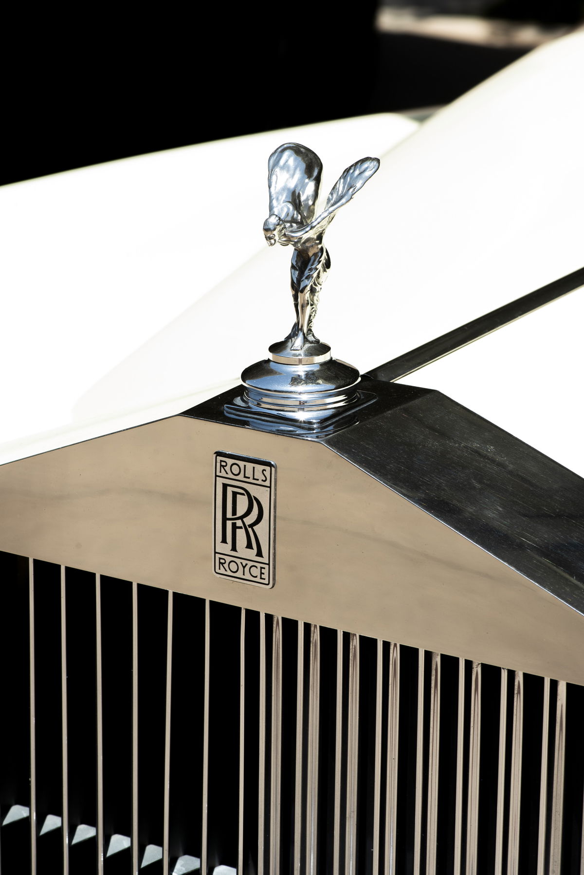 Vintage white 1963 Rolls Royce Silver Cloud parked outside a stone building storefront