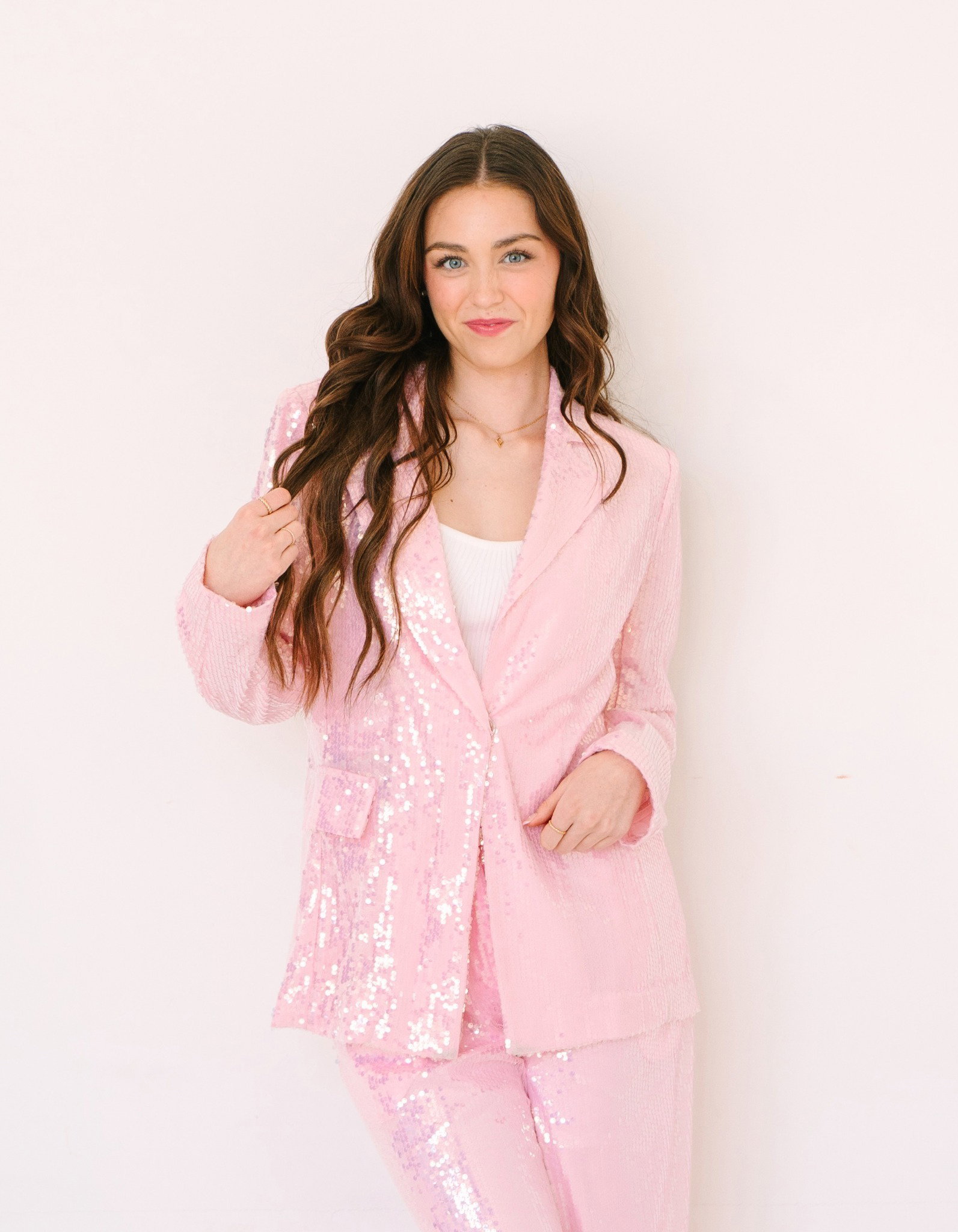 Madi Grace wearing jewelry in a pink suit.