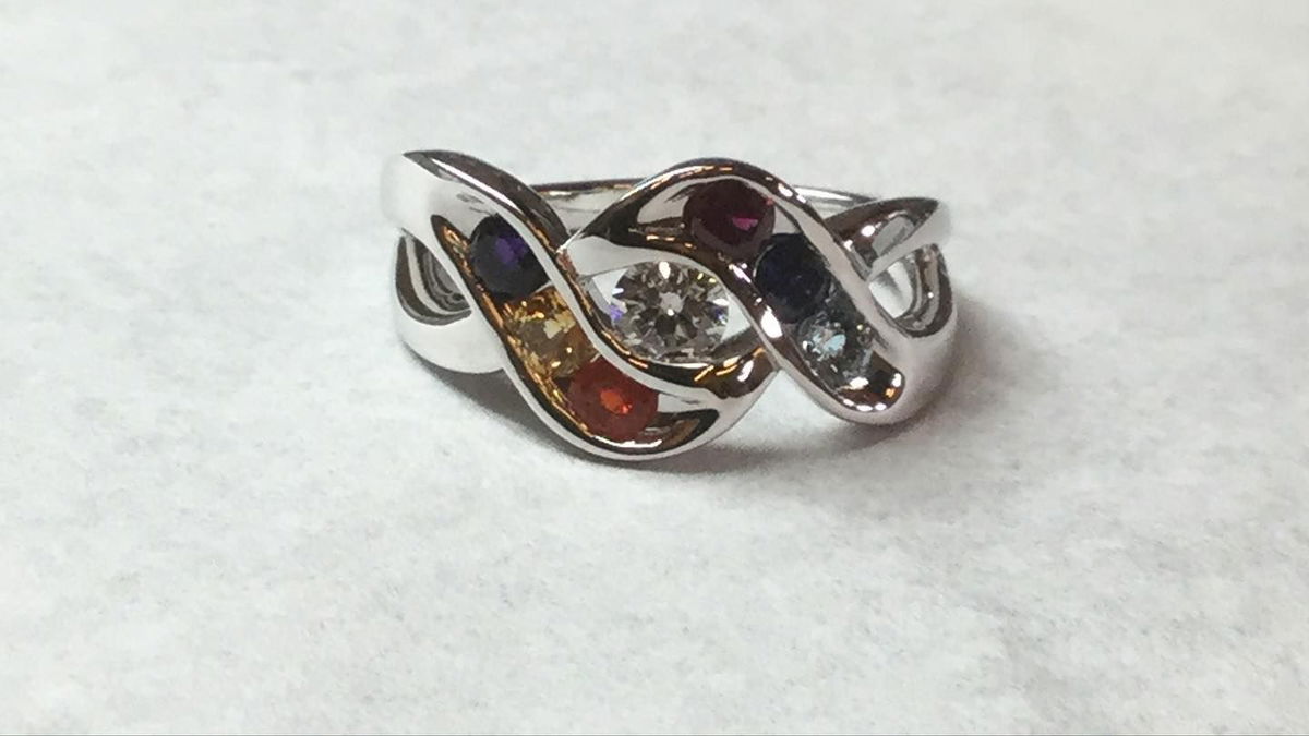 A silver ring with multicolored stones on a white surface