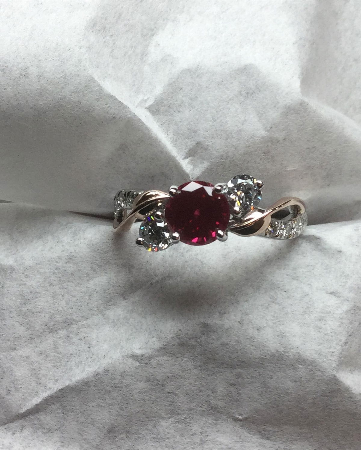 A close up of a ring with a ruby and diamonds