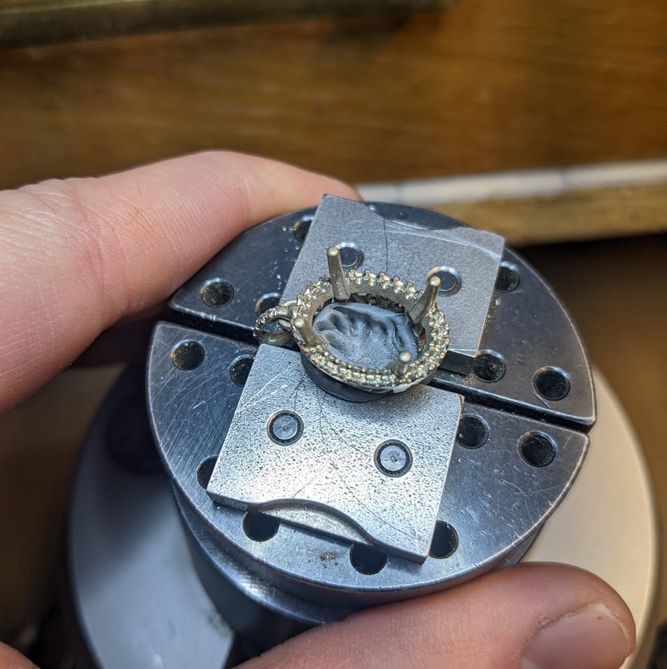 A stone being set in a ring held in a vise
