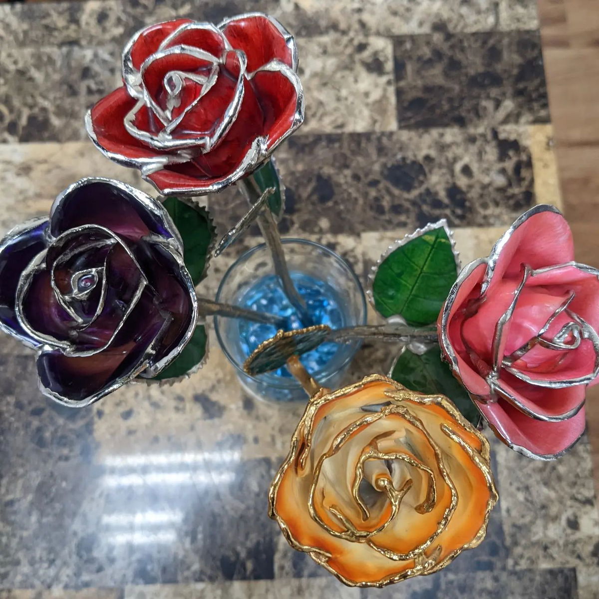 A bunch of colorful roses in a glass on a table