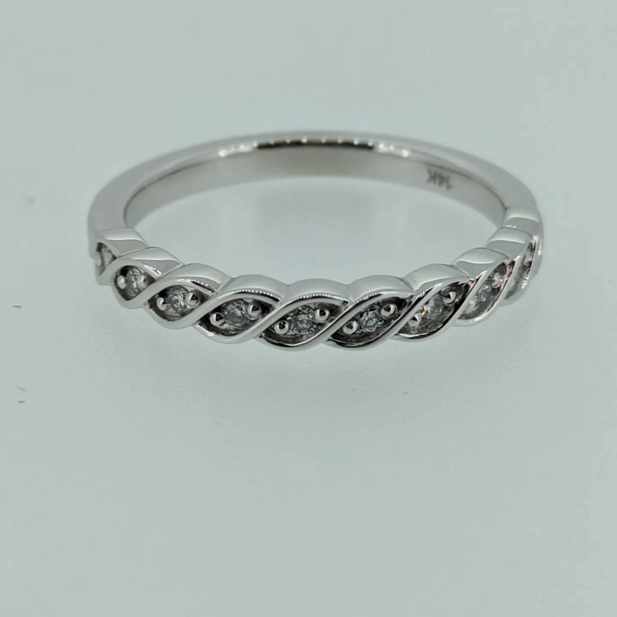 A silver ring with diamonds on a white surface