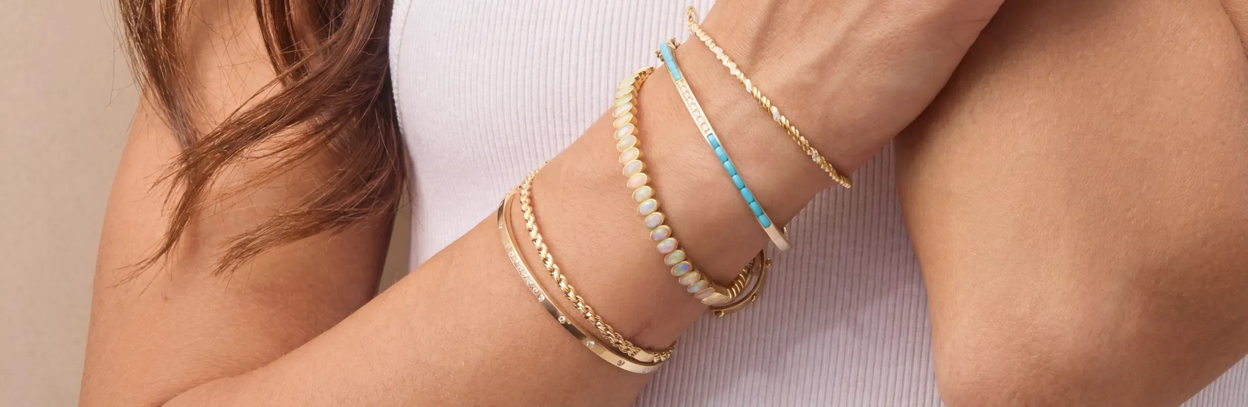 Stacked 14k gold bracelets and bangles layered on a wrist