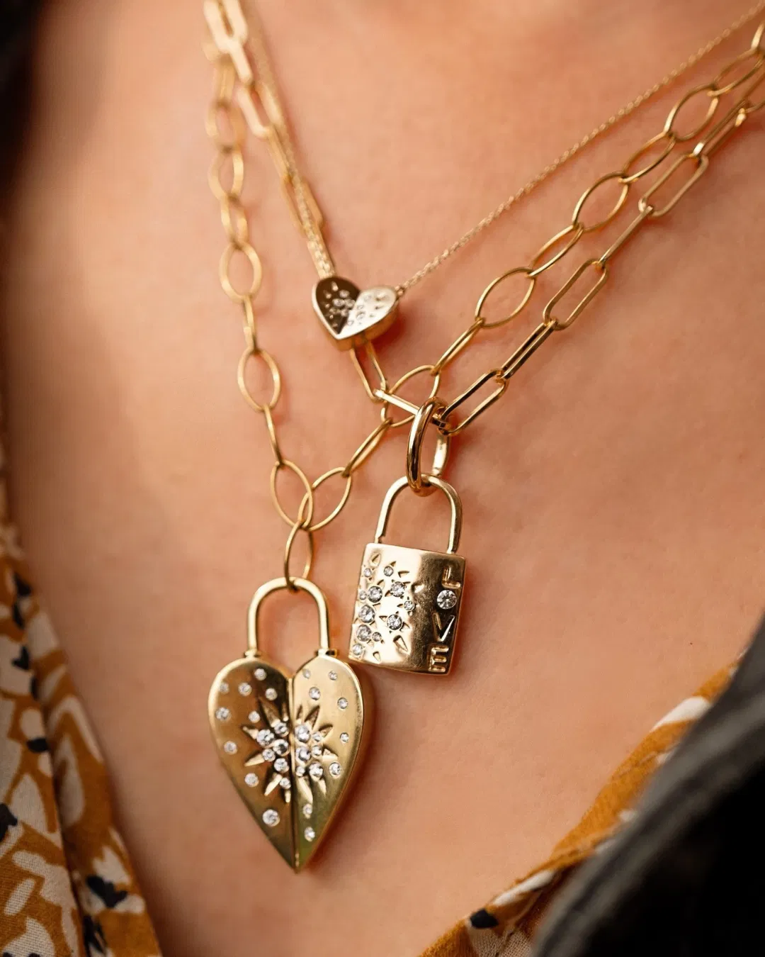 Layered 14k gold necklaces and diamond pendants on a soft neutral surface