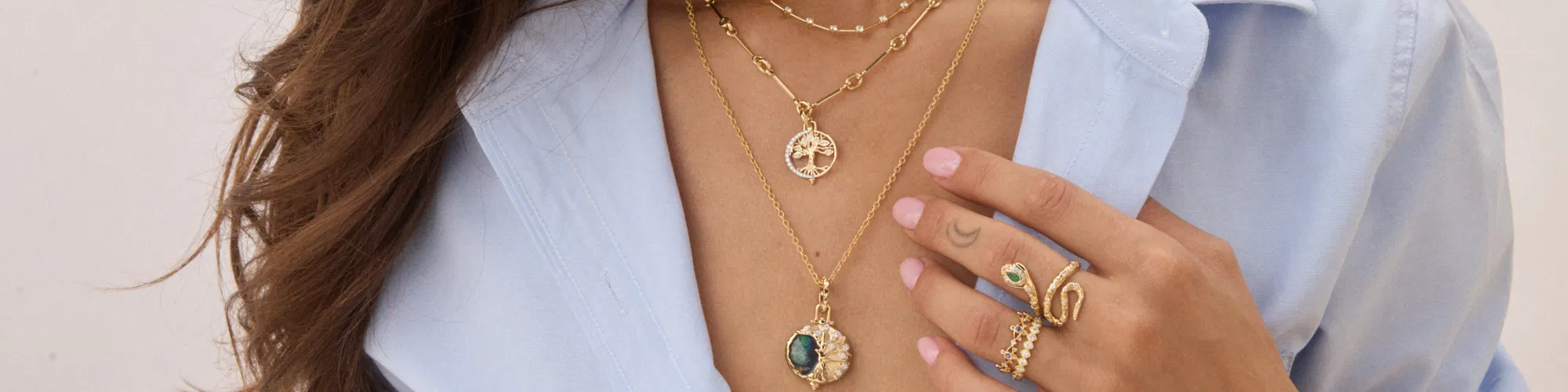 Gold jewelry pieces inspired by earth, water, fire, and air arranged on natural stone