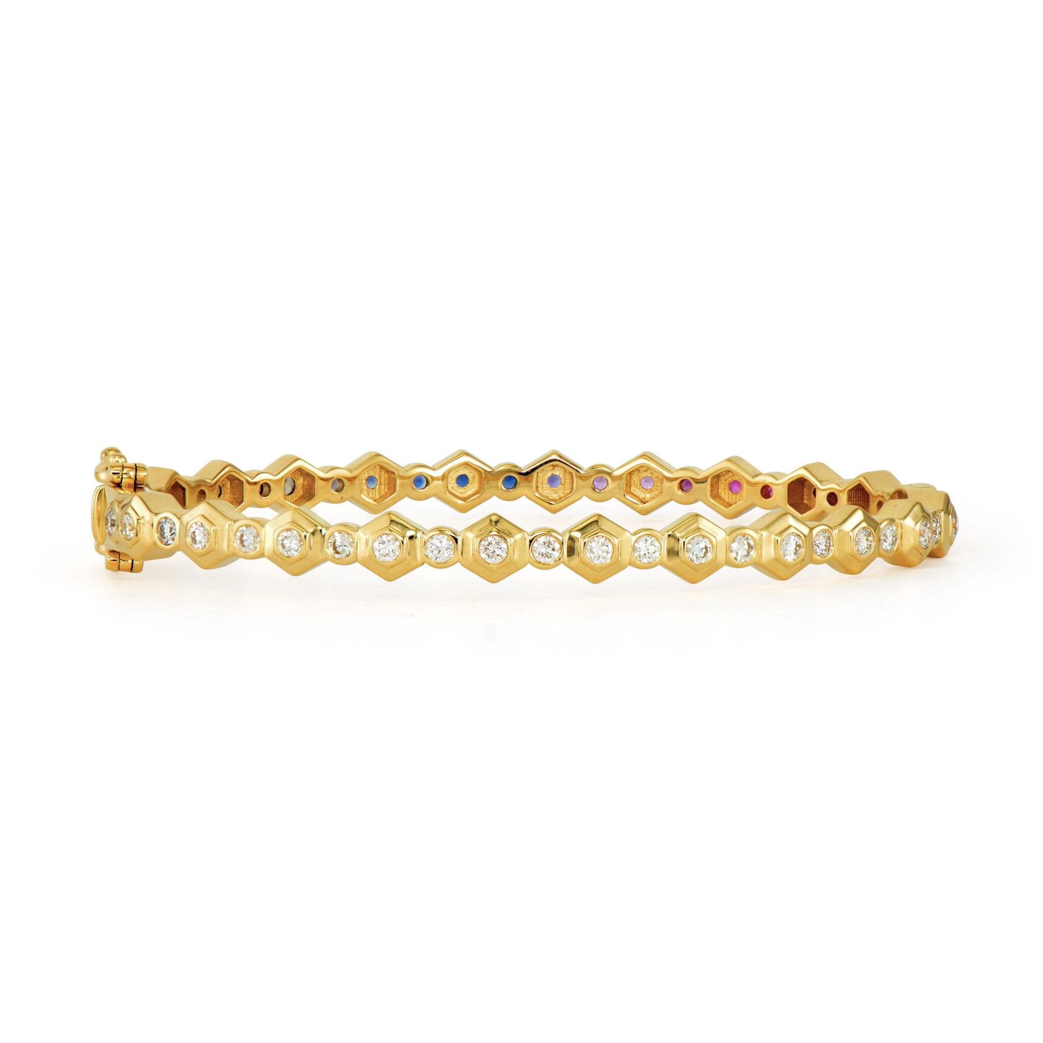 This Honeycomb Bezel Bangle brings nature's perfect geometry to your wrist. Crafted in high polished 14K gold, the distinctive honeycomb-shaped bezels create a fascinating textural pattern around the bangle. One side showcases a spectrum of rainbow sapphires, offering a vibrant play of color, while the opposite side features sparkling diamonds for classic brilliance. The honeycomb design not only provides an eye-catching structure but also securely embraces each gemstone. This versatile bangle allows you to switch between colorful flair and timeless elegance with a simple twist of the wrist. Size 6.5. Honeycomb Bezel Bangle