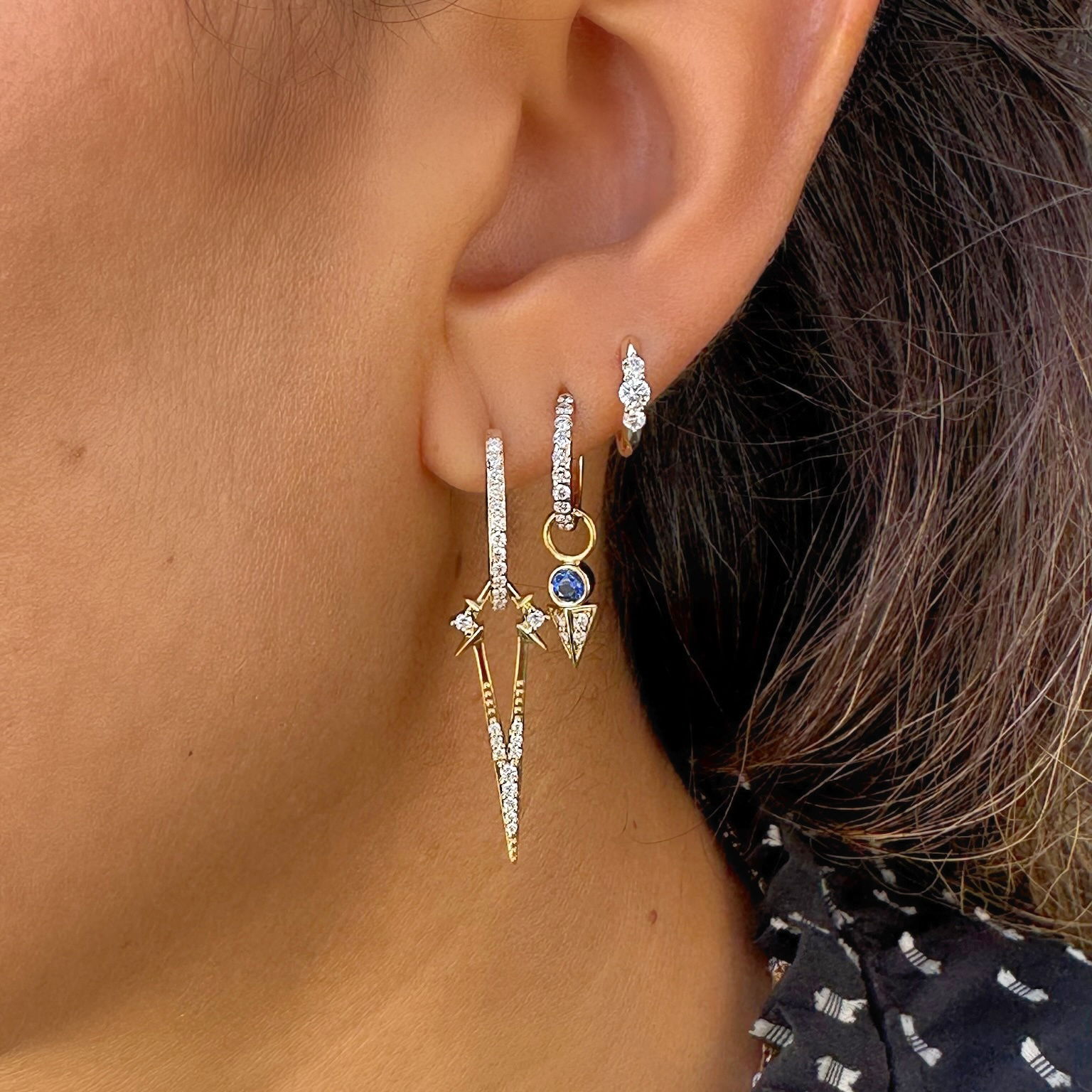 The Tiny Blue Sapphire Pyramid Charm combines celestial color with geometric elegance. Crafted in 14K gold, this delicate charm features a bezel-set blue sapphire at the top with a pavé diamond pyramid suspended below. The rich blue of the sapphire provides beautiful contrast against the sparkling diamond pyramid, creating a captivating play of color and light.The geometric pyramid shape adds modern appeal while the suspended design allows for gentle movement that catches the eye. This meaningful charm brings together ancient symbolism and contemporary style in a petite package. This sparkling gold charm can be worn on Three Stories hoop earrings or added to a chain bracelet or necklace by adding an openable pendant bale. Charms sold as singles. Hoops and charms sold separately. Tiny Blue Sapphire Pyramid Charm