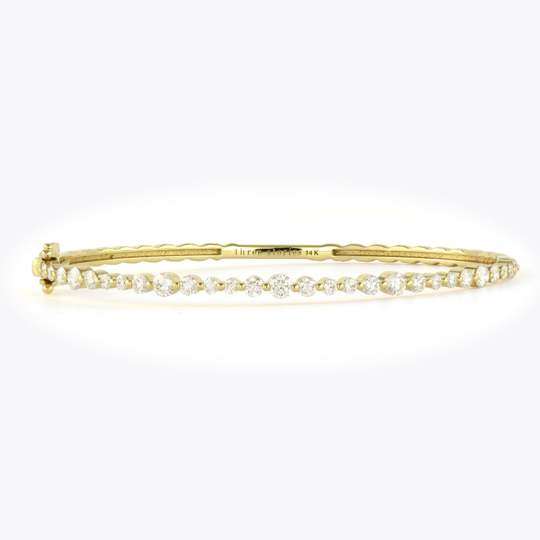 The Continuous Diamond Bangle features a brilliant line of diamonds, crafted in 14K gold for maximum impact. The back remains in smooth gold, ensuring comfortable wear, while the front delivers all the glamour. This thoughtful design places the sparkle exactly where it catches the most light and attention.Perfect for everyday luxury or special occasions, this bangle works beautifully worn alone or stacked with other Three Stories bangles. Continuous Diamond Bangle