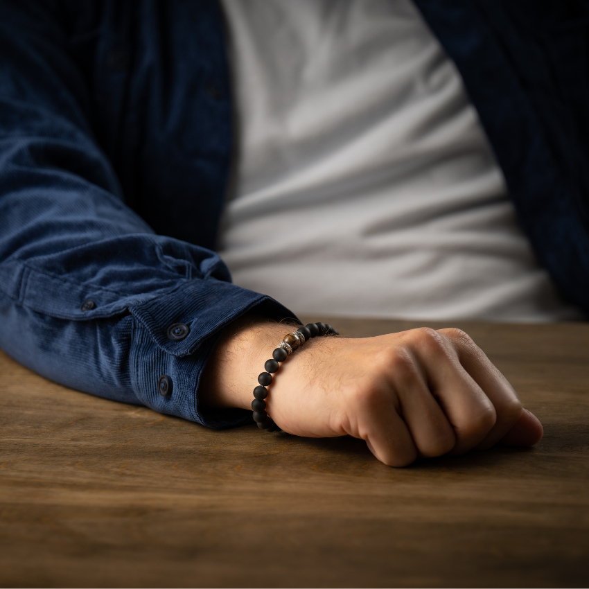 This bracelet is built around a centerpiece that features a bead crafted from 10,000 year old woolly mammoth tooth, found on the seafloor in select locations. Once harvested, the tooth has to dry for 2 years. Every bead is unique in pattern and color. Flanked by sterling silver and frosted black onyx and with a comfortable and secure sterling clasp system. Whether you are in denim or business attire, the 'Clan' wears beautifully and adds your own distinct style. Great on its own or layered with other pieces. Clan Beaded Bracelet