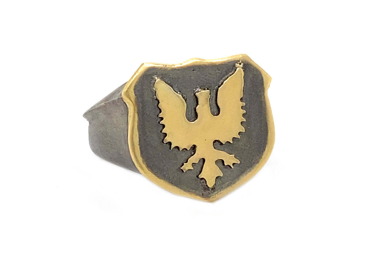 Make a bold statement with this stunning 18k yellow gold and blackened sterling silver griffin signet ring. The intricate design features a fierce griffin with wings that span across the front of the ring. The blackened sterling silver and 18k yellow gold create a beautiful contrast and eye-catching combination. With its majestic design, this ring is guaranteed to turn heads and add a powerful statement to your look. Griffin Signet Ring
