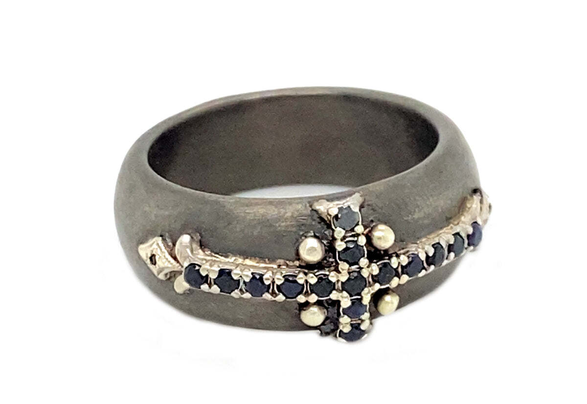 This extraordinary 18k yellow gold and blackened sterling silver ring is perfect for those who seek a modern twist on an iconic spiritual symbol. The pointed cross design features a striking contrast between the yellow gold and blackened silver, creating an eye-catching aesthetic. The cross is further set with black sapphires, adding a touch of elegance and sophistication to the design. Whether worn as a fashion statement or as a spiritual reminder, this ring will bring a unique statement to your jewelry collection. Pointed Cross Ring
