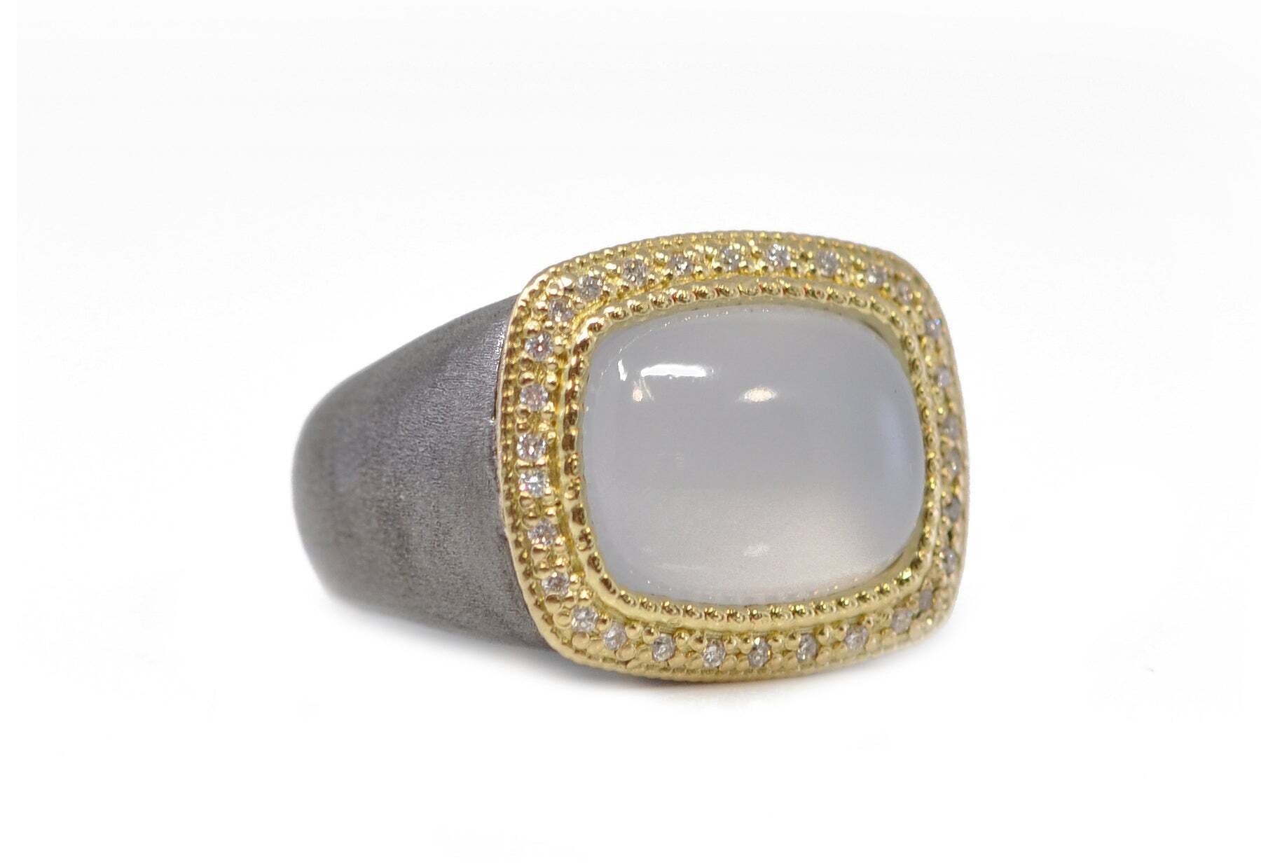 This stunning signet ring is the perfect accessory for any fashionable man. Crafted from a combination of 18K yellow gold and grey sterling silver, this statement piece boasts 0.14 carats of white diamonds and a 14x11 Turkish chalcedony in the center. With its classic style and modern design, this ring is sure to become one of your go-to pieces. Its unique combination of materials and gems make it a conversation starter and a timeless addition to any jewelry collection. TURKISH CHALCEDONY SIGNET RING