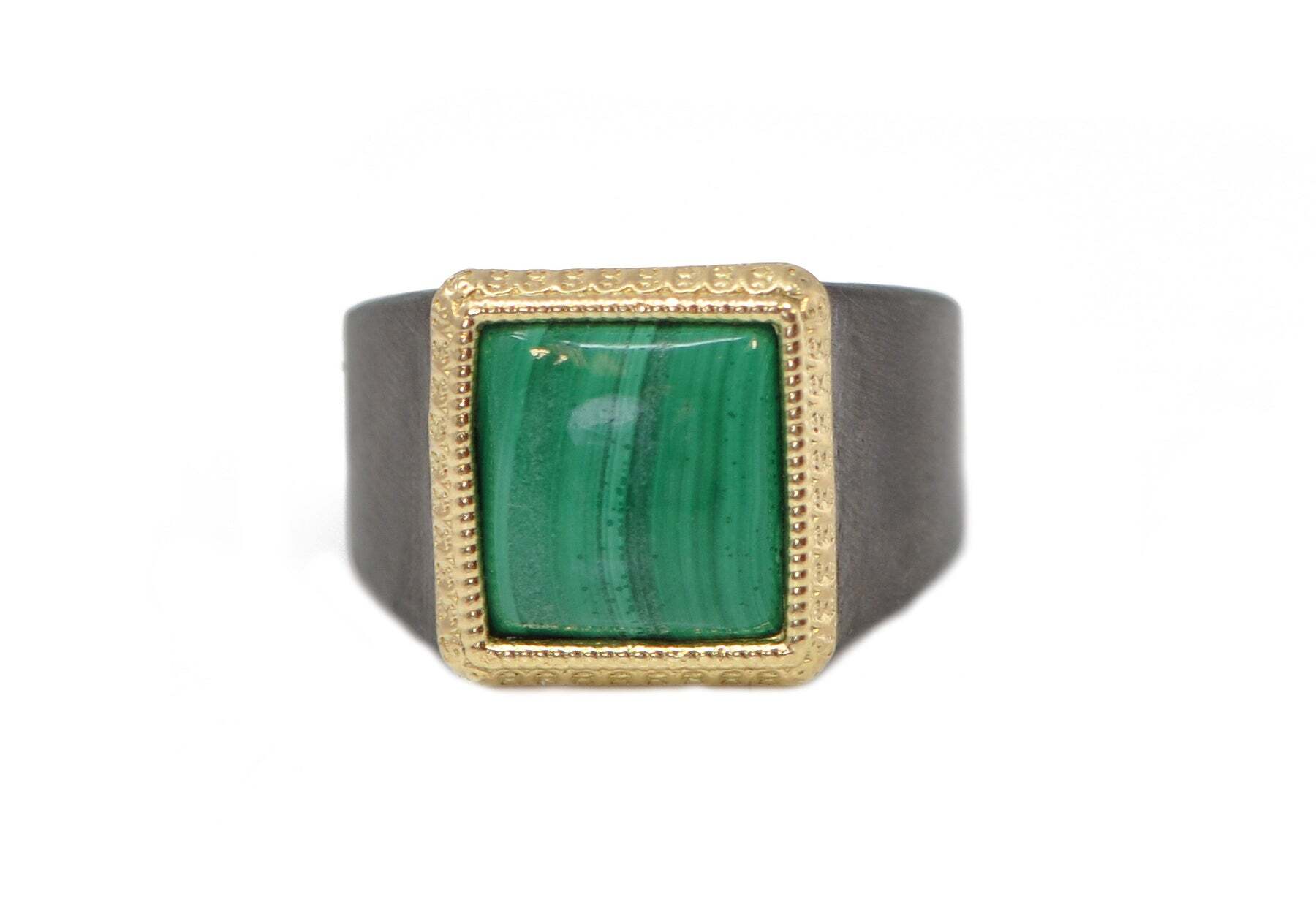 This stunning men's signet ring is the perfect way to make a subtle statement. Crafted from 18k yellow gold and blackened sterling silver, this intricate piece features a 13x12 green cabochon malachite, set into its eye-catching centerpiece. This exquisite ring catches the light in ways that will make you stand out from the crowd, while remaining timeless and classic in style. Turn heads while never compromising on your personal style with this exquisite ring. MALACHITE SIGNET RING