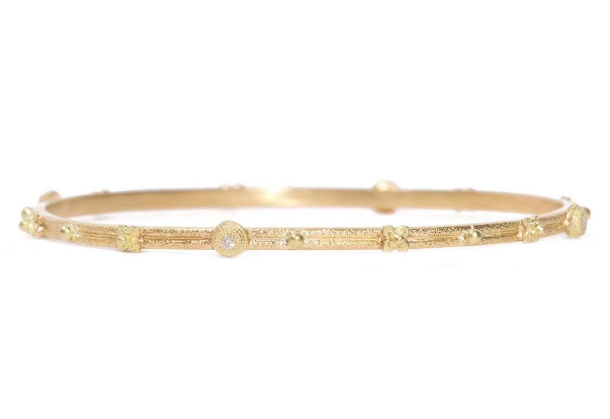 This gorgeous 18K yellow gold bangle bracelet is truly beautiful. It features "X" stations adorned with sparkling white diamonds that highlight the design. The total carat weight of the diamonds is a stunning 0.84 TCW. With its stunning shine and luxurious style, this piece is sure to be worn and admired for years to come. Station Bangle Bracelet