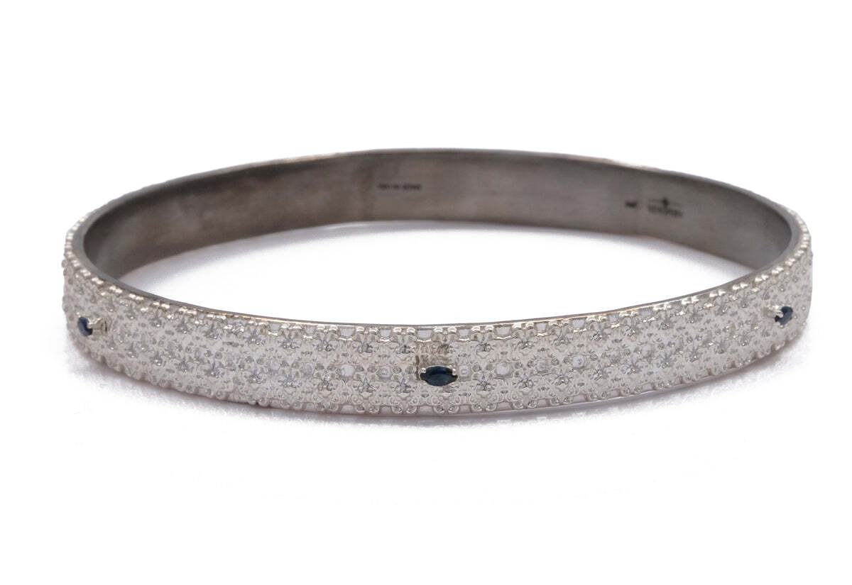 This stunning sterling silver wide textured bangle bracelet is an eye-catching accessory. The textured surface sparkles in the light and gives an elegant and sophisticated look. The oval-shaped marquise blue sapphires in the center add a beautiful touch of color and a hint of elegance. Perfect for adding a touch of glamour to your everyday look, this bracelet is sure to be a timeless piece to your jewelry collection. Wide Textured Bangle Bracelet