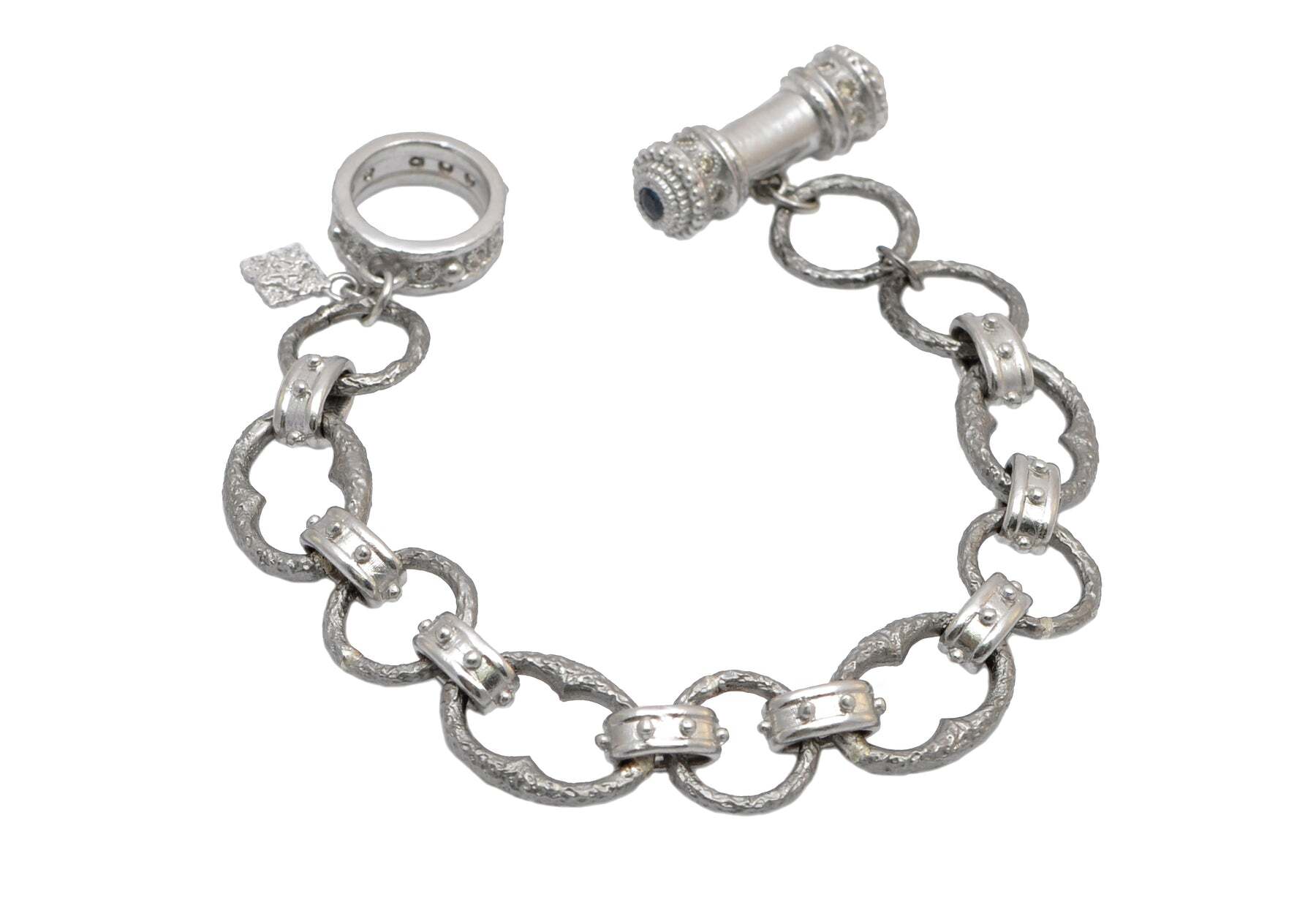 This beautiful sterling silver bracelet will add sophistication and class to whatever ensemble you choose to wear. The delicate oval chain link design features a unique heavy granulated texture. The piece is finished off with a glamorous toggle clasp that contains five shimmering blue sapphires and five sparkling champagne diamonds (0.62 TCW). This gorgeous bracelet can be worn with formal or casual attire, making it a great accessory for any occasion. Toggle Link Bracelet