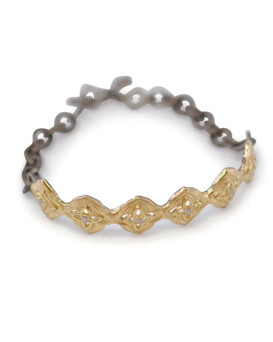 Experience luxury and style with this 18k Yellow Gold and Gunmetal Sterling Silver open scroll ID bracelet with white diamonds. The 18-karat yellow gold and gunmetal sterling silver give a sophisticated and timeless look, while the open scroll design with white diamonds adds a touch of sparkle. The bracelet is designed to be both comfortable and secure, and its ID plate makes it a great way to personalize your look. Whether you're wearing it alone or adding it to your arm-party stack, this beautiful bracelet is sure to be a timeless addition to your jewelry collection. Open Scroll ID Bracelet