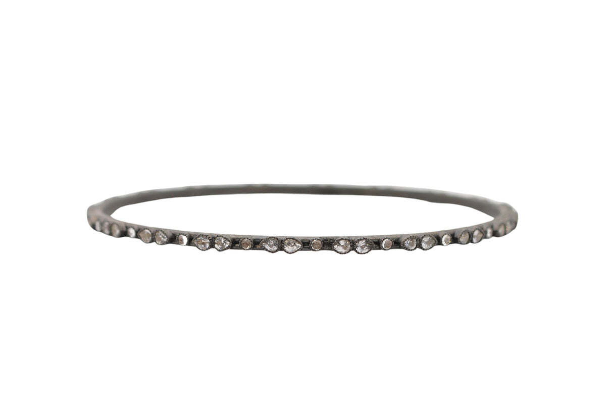 This Blackened Sterling Silver scattered Pear and Round White Sapphire bangle bracelet is sure to turn heads. Featuring a bold mix of scatted pear shaped and round cut white sapphire stones, this bangle bracelet is all glamour. The blackened sterling silver adds an edgy touch and ensures this bangle will be the star of any ensemble. With its stylish X-LARGE size, you'll be sure to stand out in any crowd. Blackened Scattered Sapphire Bangle Bracelet