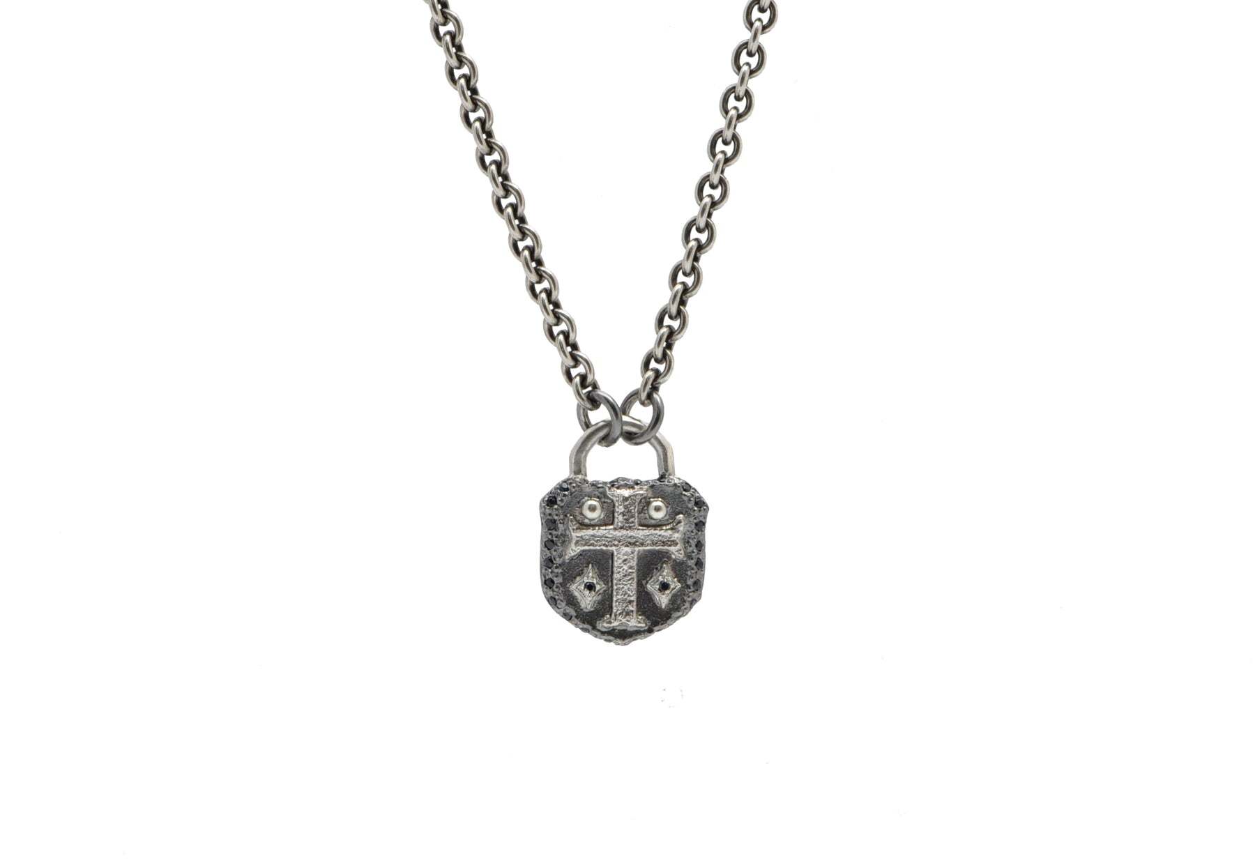 This stunning sterling silver necklace is the perfect accessory for any outfit. Featuring a gorgeous cross shield pendant with shimmering grey and sterling silver accents, this piece is elevated by two black sapphires for a look of subtle luxury. The adjustable chain can be worn at either 20" or 22", making it perfect for any occasion. Crafted with quality materials, this necklace is sure to become an everyday favorite. Cross Shield Necklace