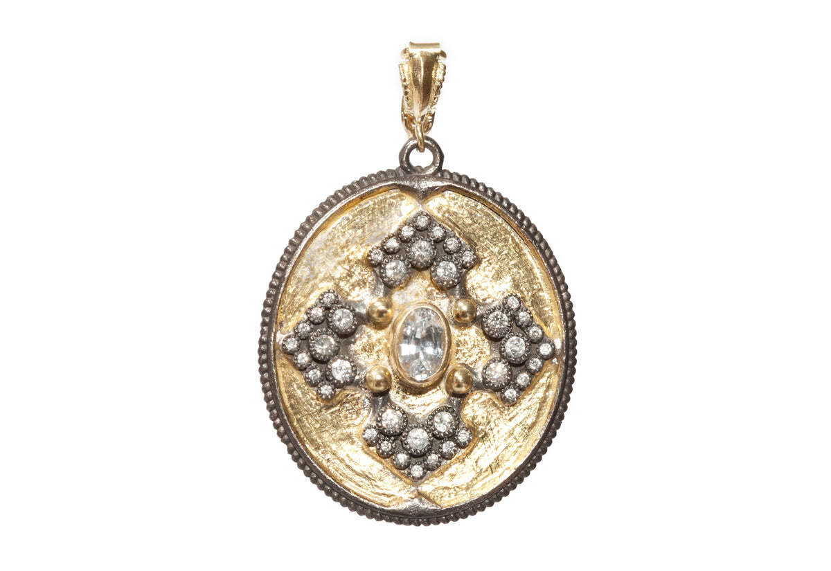 This breathtaking pendant is made from an exquisite combination of 18K yellow gold and blackened sterling silver. Perfectly proportioned in an oval pointed design, it features a raw diamond center that is surrounded by round white sapphires and white diamonds. Together, they offer 0.14 TCW of brilliance! Measuring 34mm in length and 30mm in width, this pendant offers the perfect balance of luxury and elegance. It is a truly exquisite piece that will make a statement wherever you go! Oval Iris Pendant