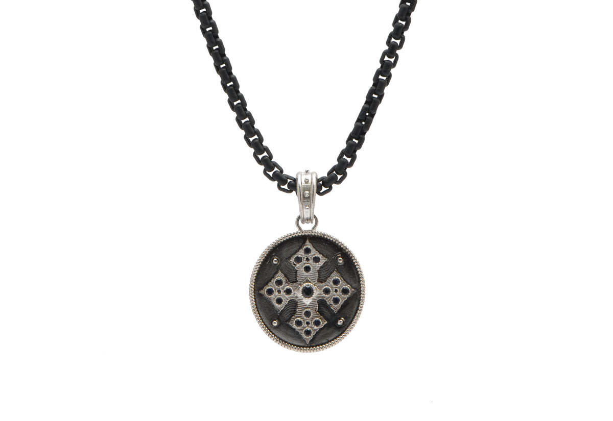 This stunning cross medallion pendant necklace is crafted from a combination of sterling silver and blackened sterling silver and features six black sapphires for added sparkle. The delicate pendant hangs from a 22" long sterling silver chain, making it the perfect accessory to add a touch of faith and beauty to your look. The intricate detailing and mesmerizing stones make this necklace an eye-catching accessory that you won't want to take off! Cross Medallion Necklace