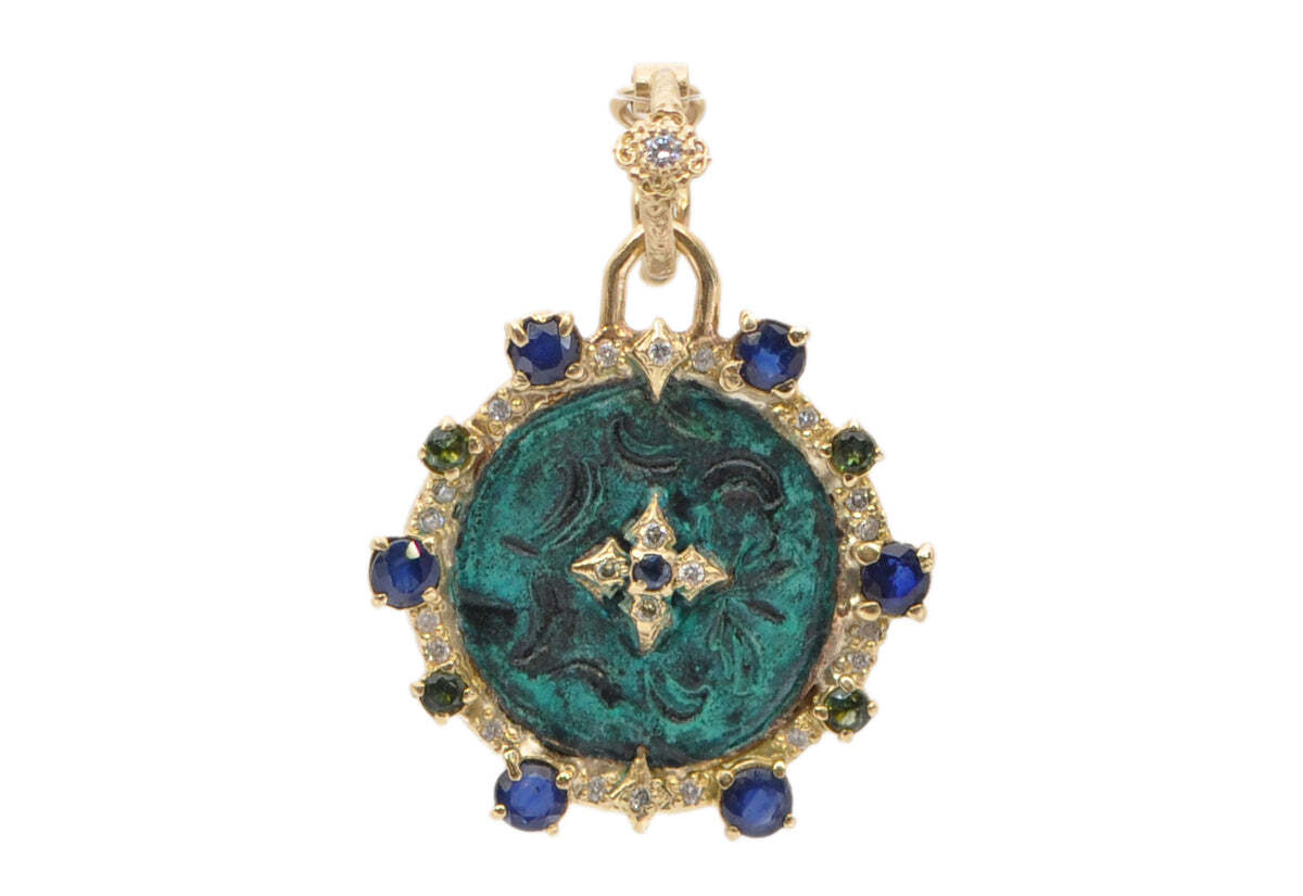 This exquisite 18k Yellow Gold 27mm Artifact Round Enhancer is decorated with a beautiful Crivelli design and encrusted with Blue Sapphires, Green Tourmaline and White Sapphires for a colorful, unique look. It also features a stunning .13TCW of Round White Brilliant Diamonds for additional sparkle and shine. Measuring 27mmx24.57mm with a con bail of 32.42, this enhancer is sure to turn heads and make a statement. 27MM ROUND ARTIFACT ENHANCER