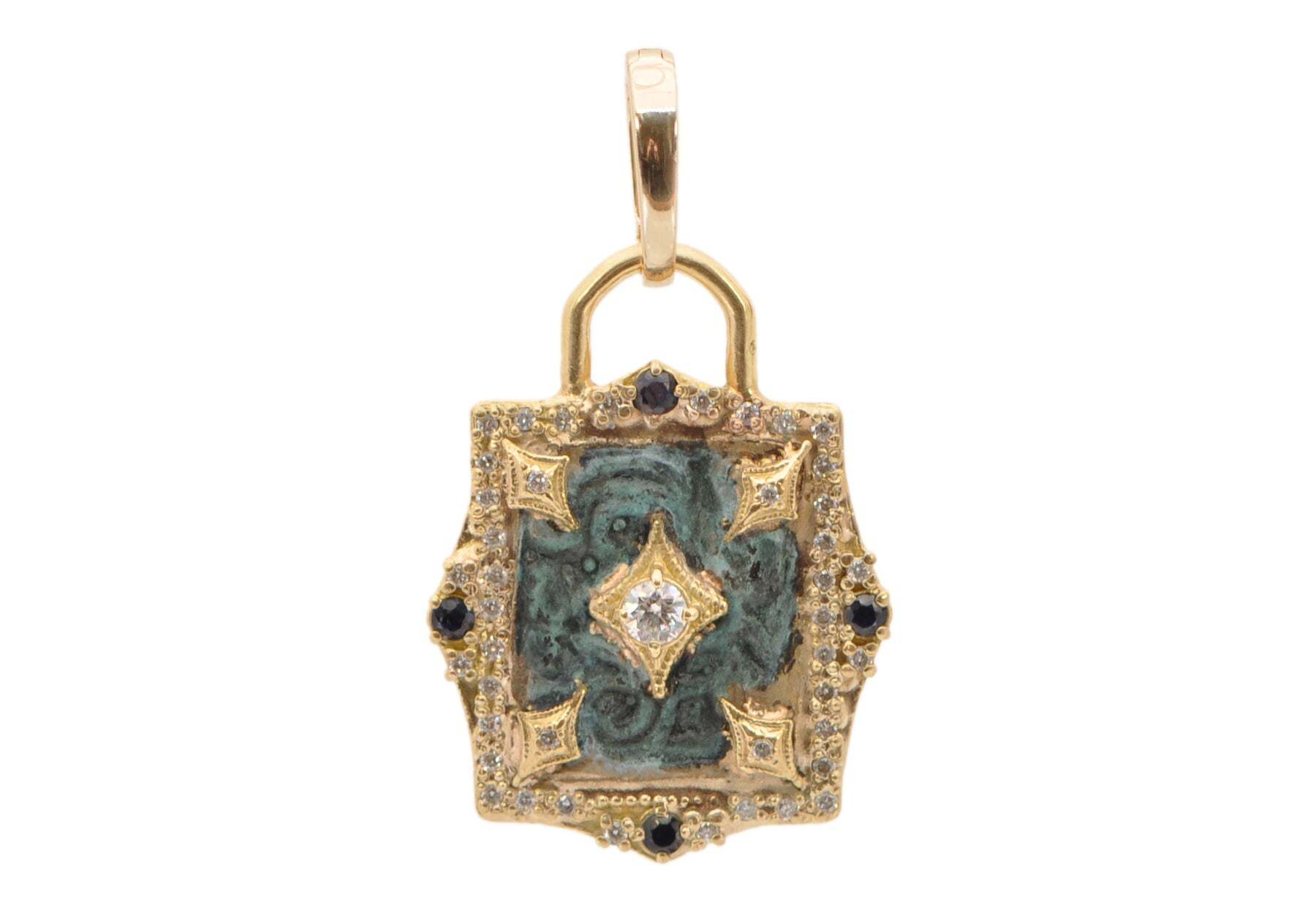 This stunning 18K yellow gold and brass artifact shield charm lock is imbued with an alluring teal patina and decorated with beautiful crivellis and 0.31TCW round white brilliant diamonds. The piece is further elevated by the addition of blue sapphires, adding a brilliant sparkle that draws the eye. This unique item is sure to become a treasured piece in your jewelry collection. ARTIFACT SHIELD CHARM
