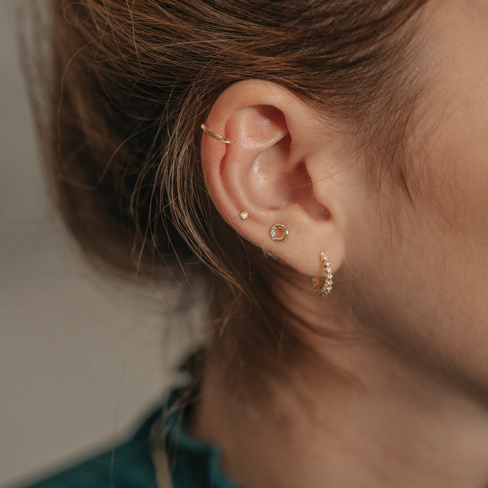 This high-quality solitaire piercing stud earring exudes a modern classic style, sparkling with a round brilliant cut diamond. This sparkling diamond sits nestled securely in a bezel setting that will not get caught on clothing or hair with its smooth finish and sleek lines. This petite high-quality diamond piercing stud earring is hypoallergenic, non-corrosive, and non-toxic. The small size makes this diamond stud suitable for a variety of different brand new ear piercings, including cartilage and lobe. GERI | Bezel Diamond Threadless Flatback Earring