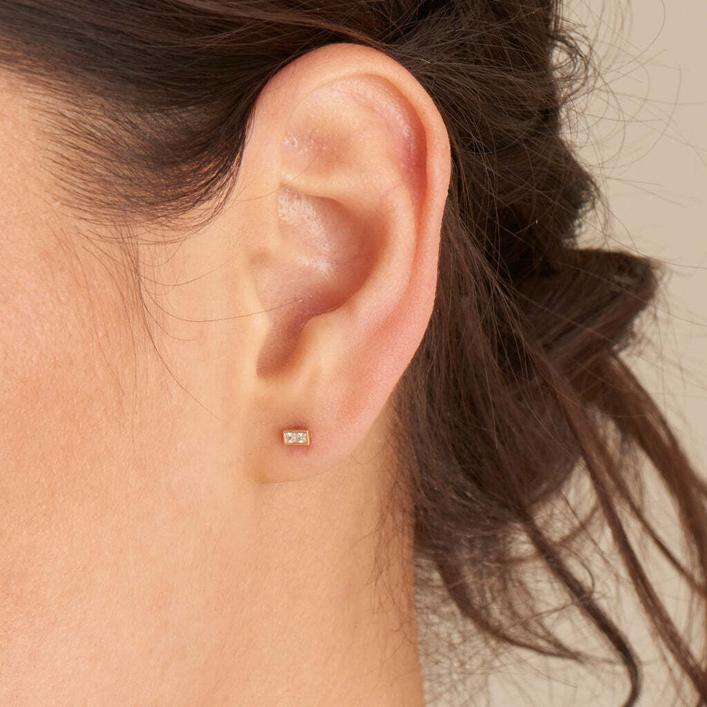 Craving some glam in your collection this season? Us, too. Try adding an edge to your ear party with these luxe cubic zirconia gold stud earrings. Mini in size but major when it comes to hitting the trends. Finished in a modern angular shape with a duo of square stones in each stud, style them with chunky huggies for the perfect seasonal ear stack. Glam Mini Stud Earrings