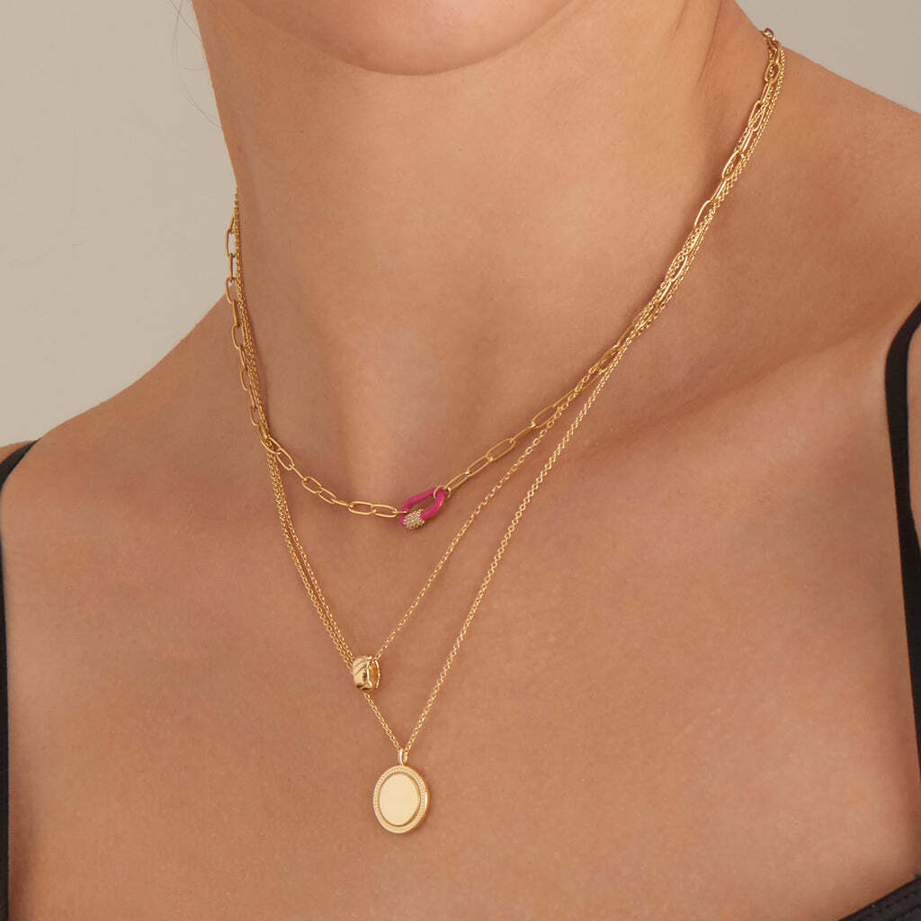 Enamel jewelry and neon brights is the trend collaboration we never knew we needed until now! Inspired by a classic carabiner, this chunky chain necklace pairs up with a neon pink enamel pendant for the perfect finishing touch. With an added glimpse of sparkle through the cubic zirconia detailing, it’s the perfect piece to add to your look for all your festival and holiday looks this season. Wear it solo for a fun and vibrant pop of neon color or layer it up with coordinating pieces for a striking neon rainbow. Designed with versatility in mind, this necklace is reversible and can be worn facing the other way with a plain gold finish, giving you a two-in-one option and the ultimate choice in flexible styling. Neon Pink Enamel Carabiner Gold Necklace