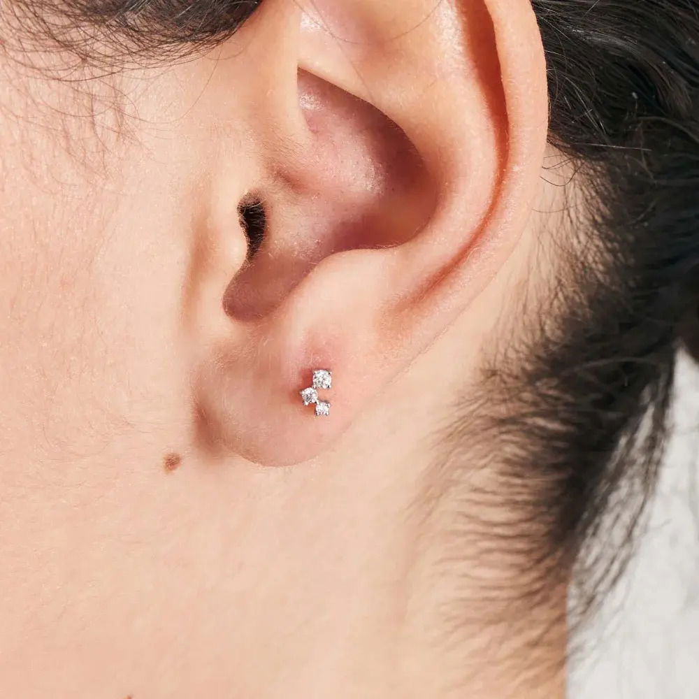 Opt for some truly special sparkle this season designed into one chic single barbell with this unique stud. Stacking triple the sparkle with three cubic zirconia stones, this asymmetric stud is perfect for lobe, helix, conch, or tragus piercings and pairs perfectly with chunky gold huggie hoops and a row of shimmering simple studs. Gold Sparkle Galaxy Barbell Single Earring