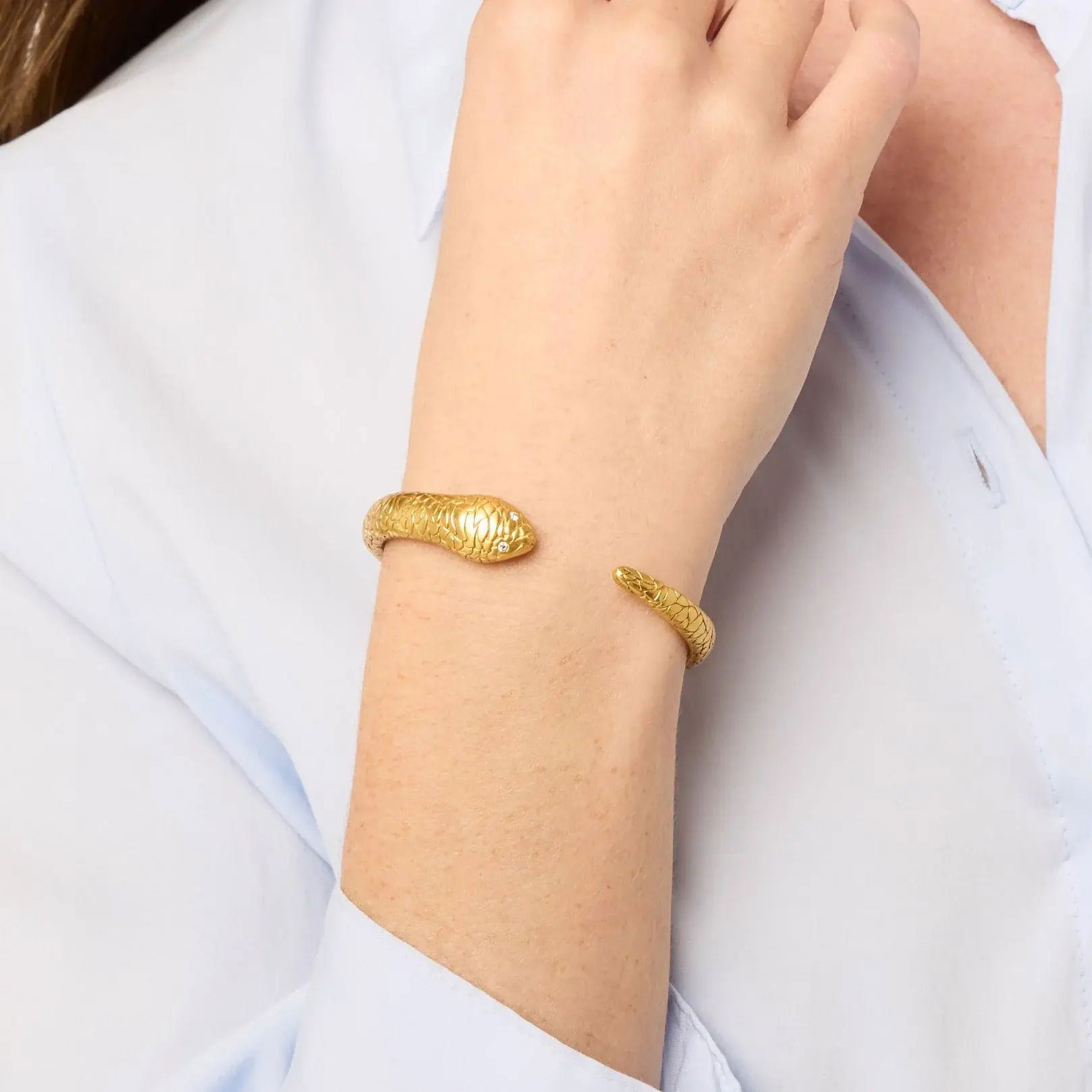 Lithe, lifelike, and luxurious, this golden serpent cuff shimmers in the sunlight, with abstract geometric scales and glittering gemstone eyes. Snake Cuff