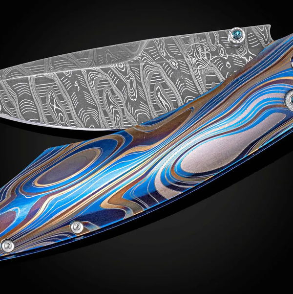 Closeup photo of Blue Demon- Color laser-engraved titanium pocket knife with hand-forged damascus blade