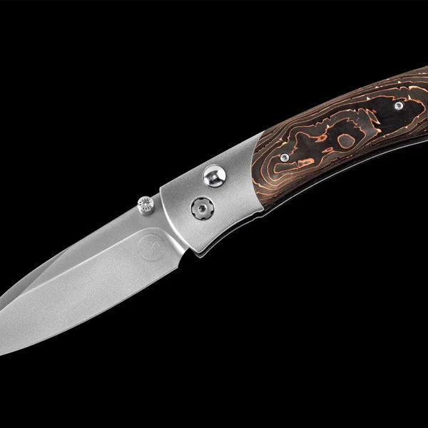 Closeup photo of Titanium pocketknife with compressed copper swirl carbon fiber and stainless blade